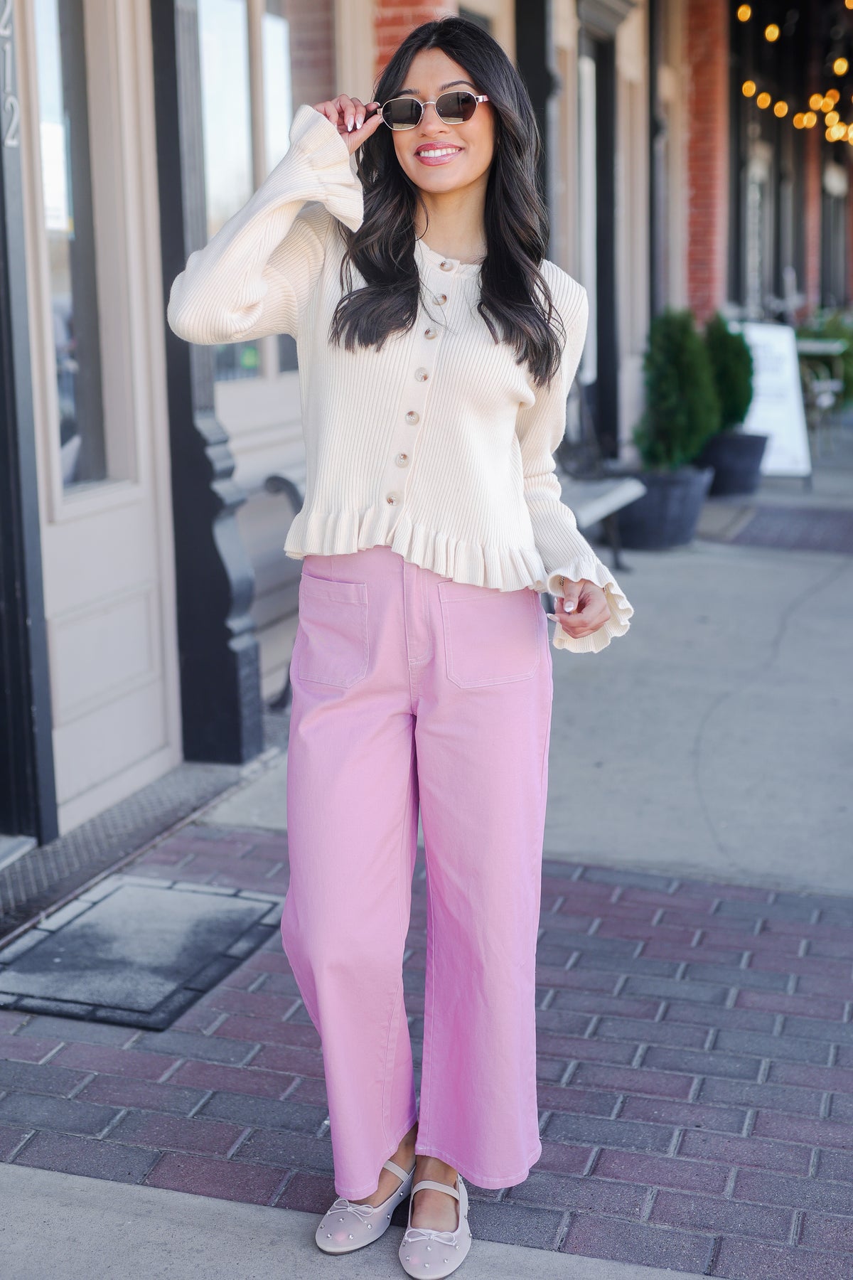 Woman wearing a white blouse and pink pants on a city street.