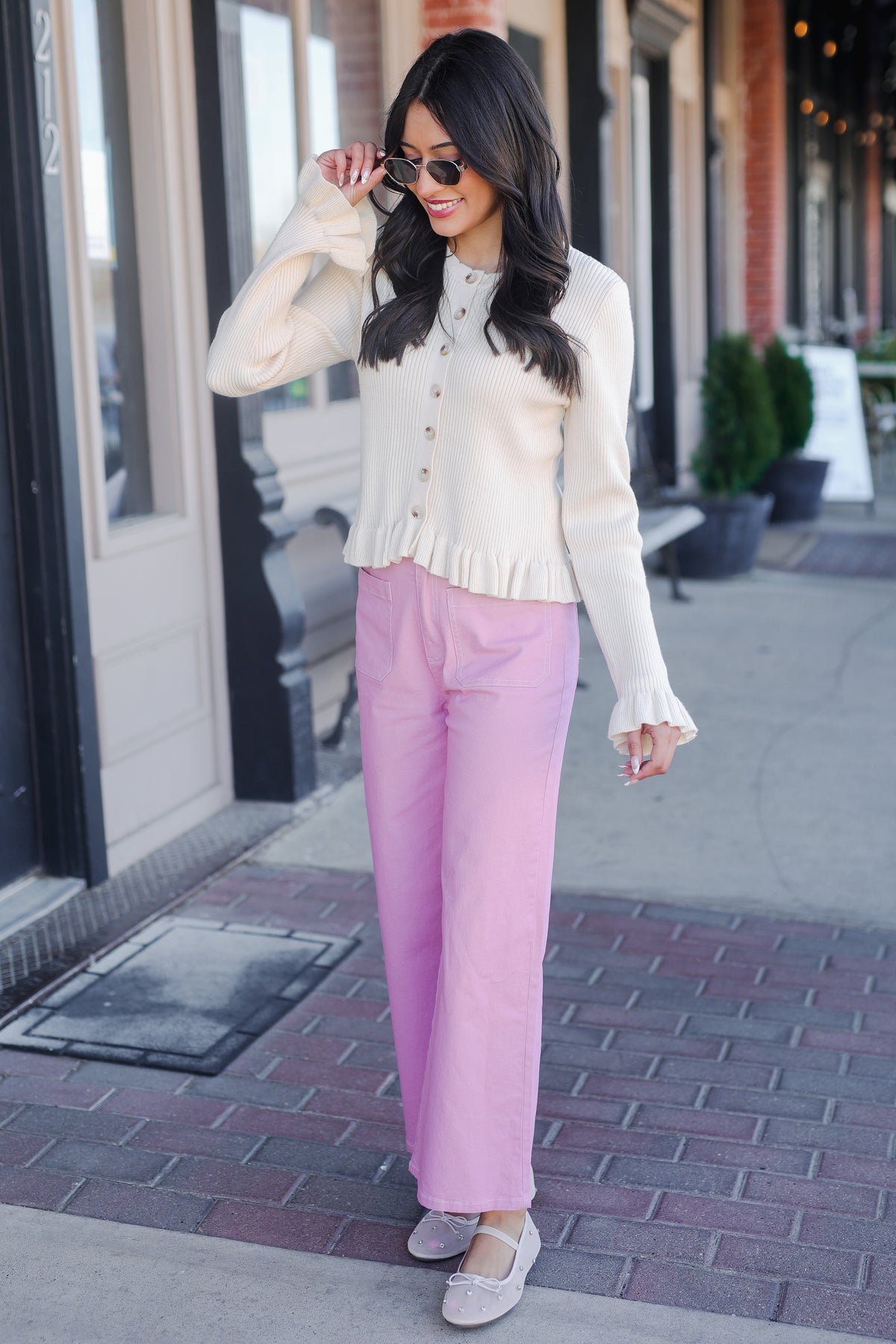 Woman wearing a white blouse and pink pants on a city street.