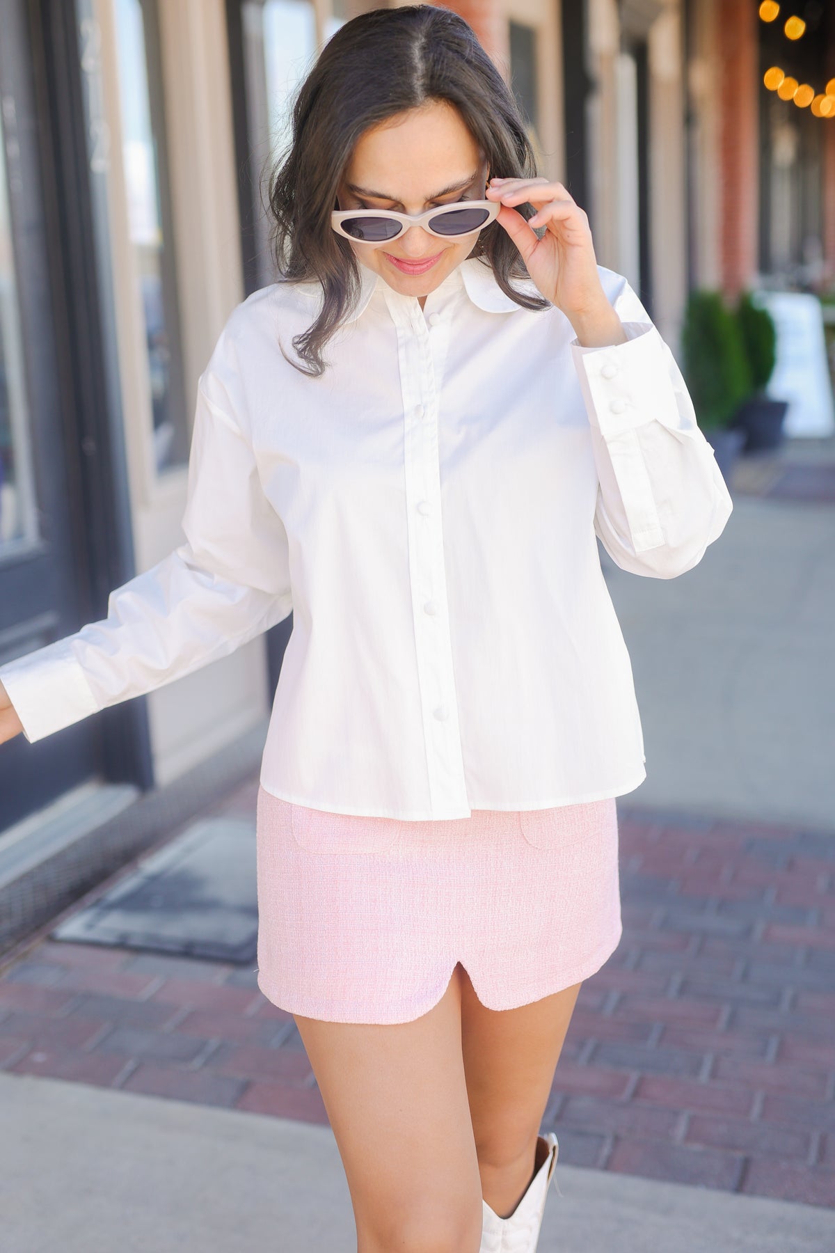 Woman wearing a white shirt and pink shorts on a city street.