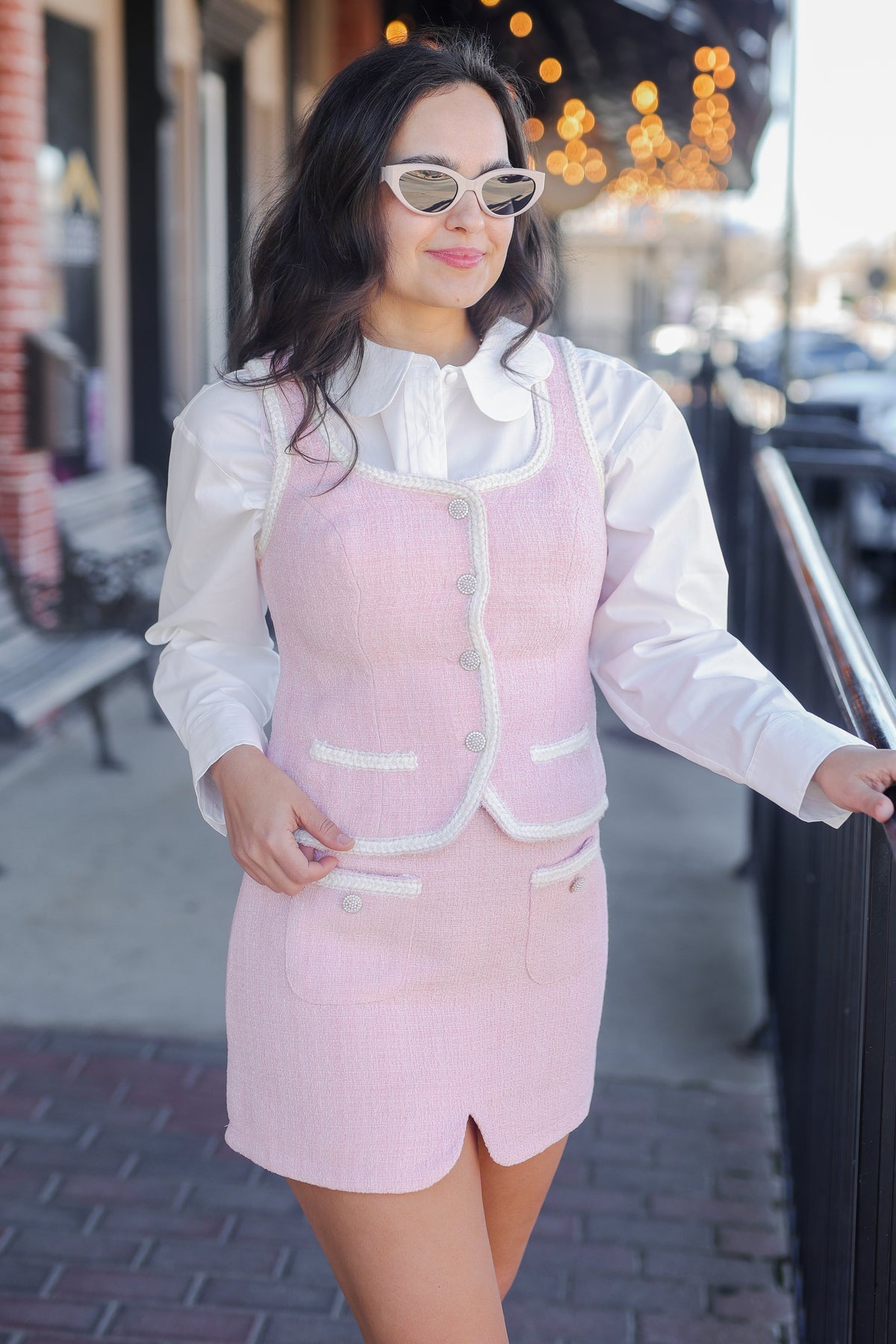 Woman wearing a light pink dress with a white shirt in an urban setting