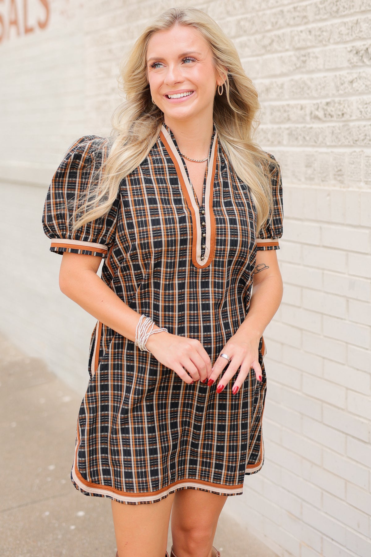 Blonde model standing outside wearing a black multi colored dress with tan boots.
Southern House Clothing