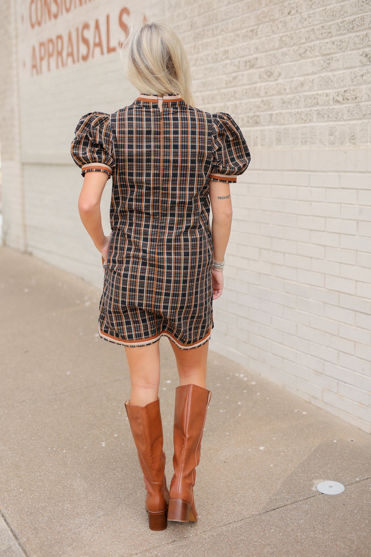 Blonde model standing outside wearing a black multi colored dress with tan boots.
Southern House Clothing