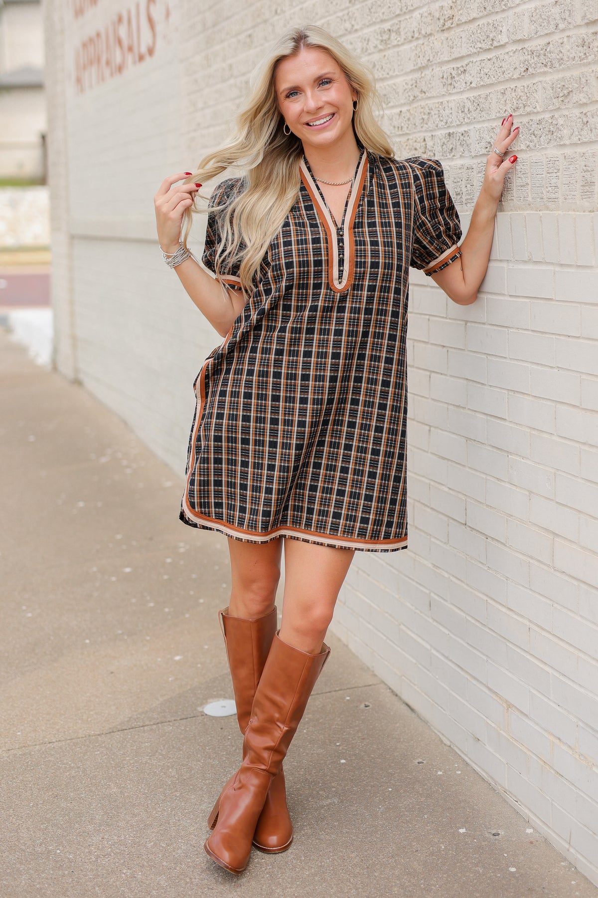 Blonde model standing outside wearing a black multi colored dress with tan boots.
Southern House Clothing