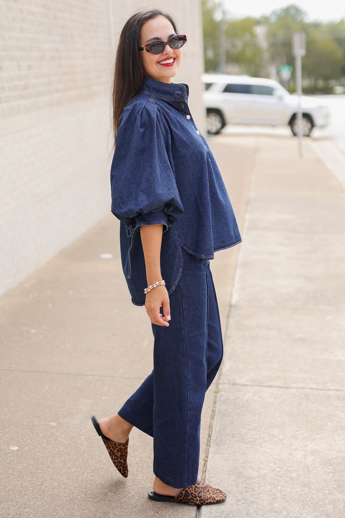 Model wearing the Westhaven Puff Sleeve Denim Top in Dark Wash with Langley Pants and Atlas Leopard Hair Shoes, styled with a red statement necklace. Southern House Clothing