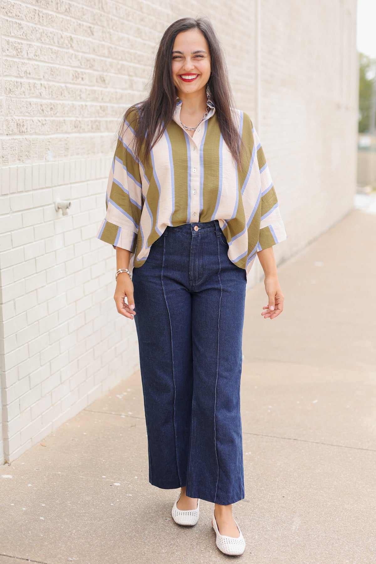 Model wearing Mabank Stripe Button-Up Top in olive green, ivory, and light blue with an oversized fit, collared neckline, and wide sleeves, styled with the Langley dark-wash jeans. Southern House Clothing
