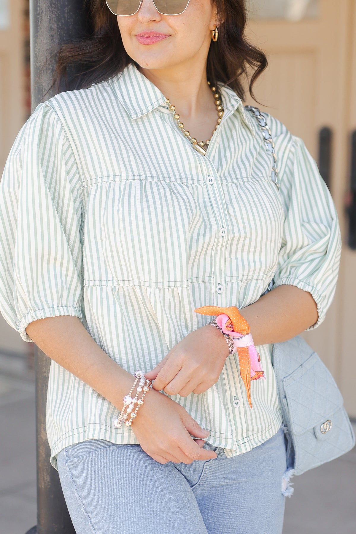 Woman wearing a striped shirt and jeans with colorful bracelets outdoors.