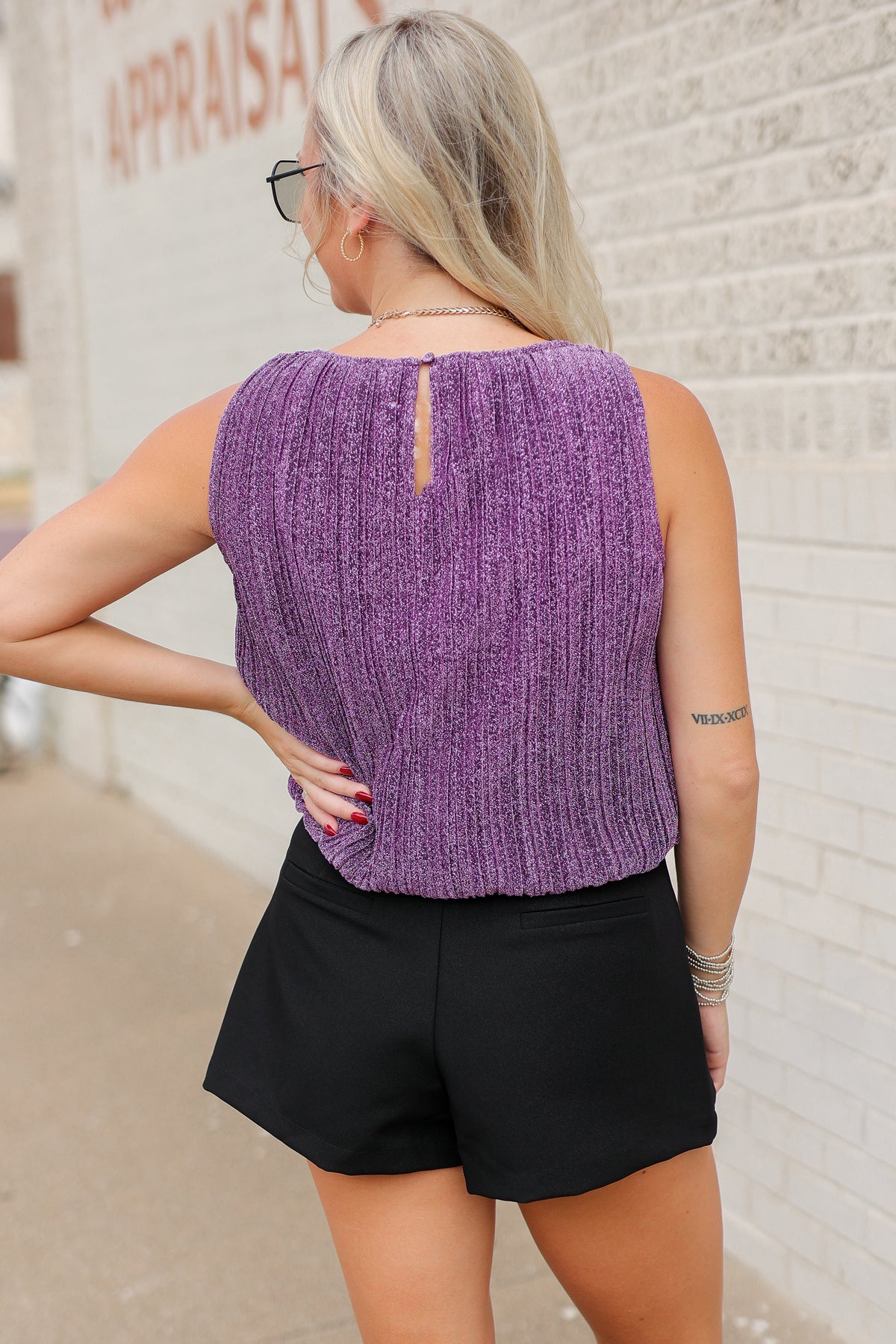 Blonde model standing outside wearing the Tiverton Textured Tank in purple featuring a sleeveless design and textured vertical ribbing, styled with the Orlena Button black wrap skort and the Kevin embroidered black cowboy boots. Southern House Clothing