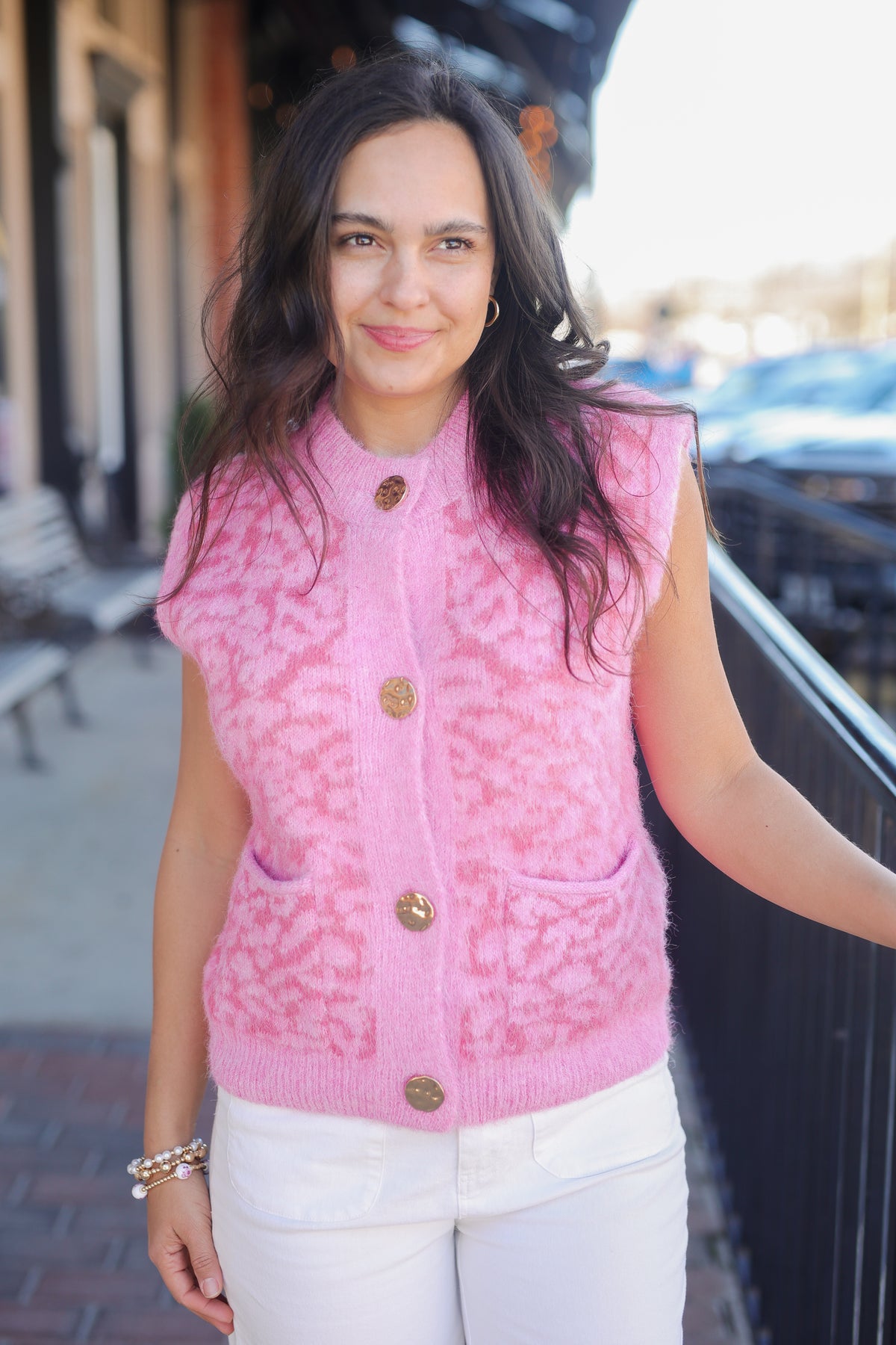 Woman wearing a pink vest with gold buttons outdoors