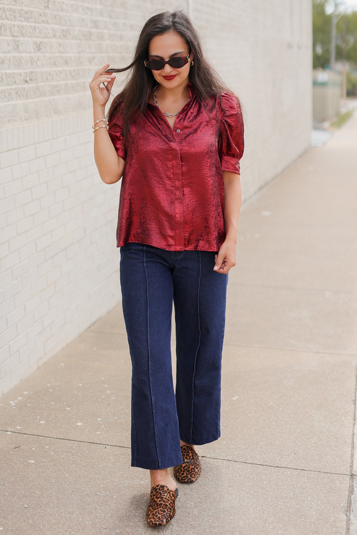 Model wearing the Bellmont Satin Puff Sleeve Blouse in Burgundy with dark-wash wide-leg jeans called the Langley, leopard-print flats called the Atlus, and silver jewelry for a chic casual outfit. Southern House Clothing
