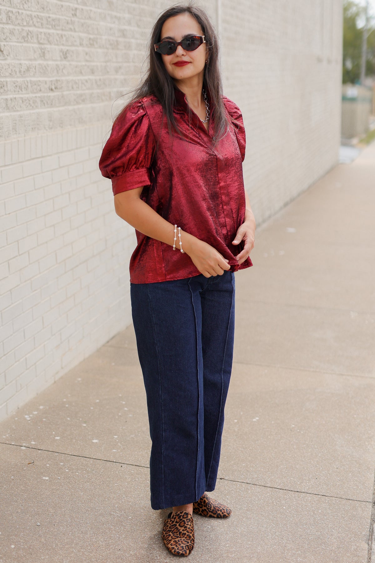 Model wearing the Bellmont Satin Puff Sleeve Blouse in Burgundy with dark-wash wide-leg jeans called the Langley, leopard-print flats called the Atlus, and silver jewelry for a chic casual outfit. Southern House Clothing