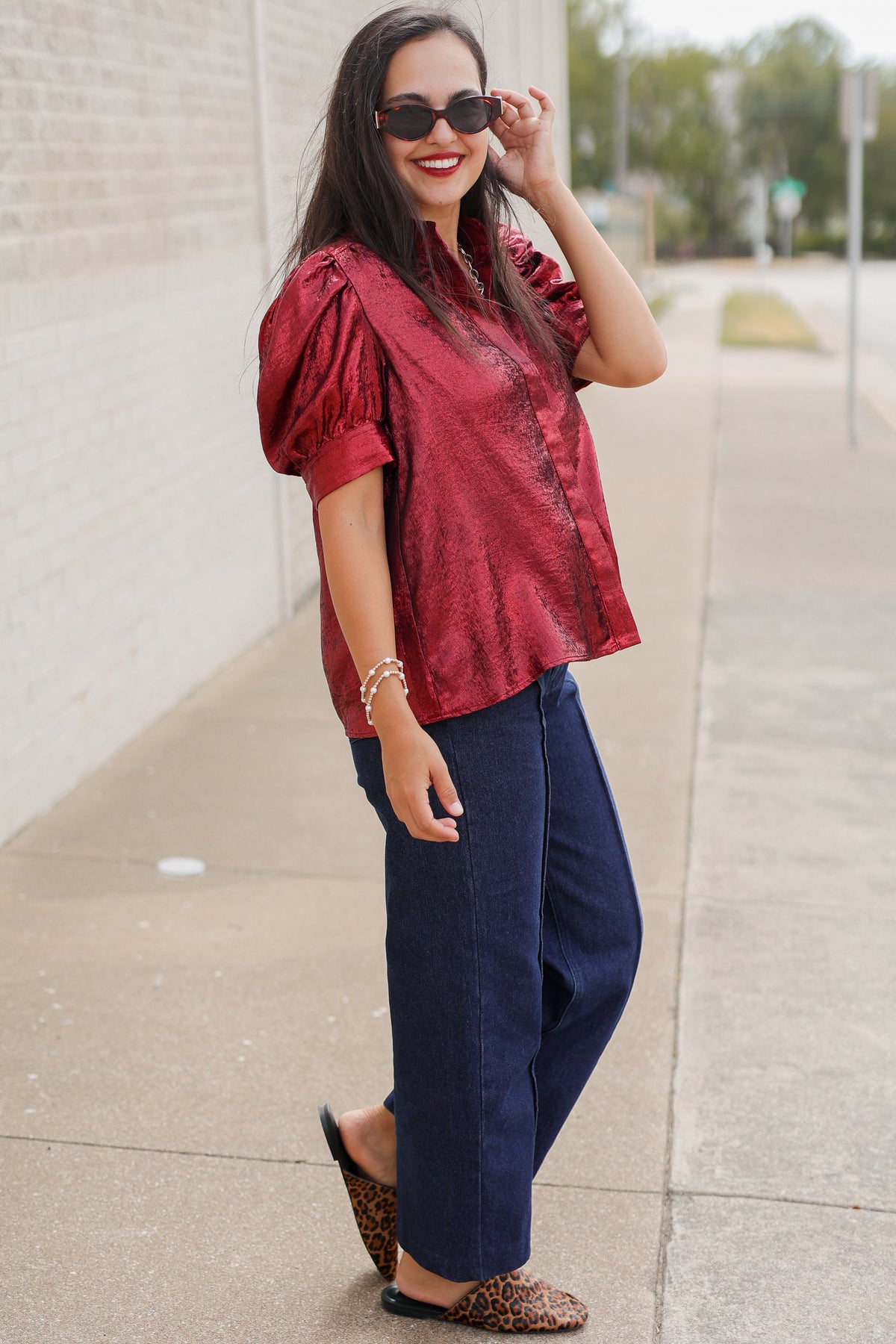 Model wearing the Bellmont Satin Puff Sleeve Blouse in Burgundy with dark-wash wide-leg jeans called the Langley, leopard-print flats called the Atlus, and silver jewelry for a chic casual outfit. Southern House Clothing