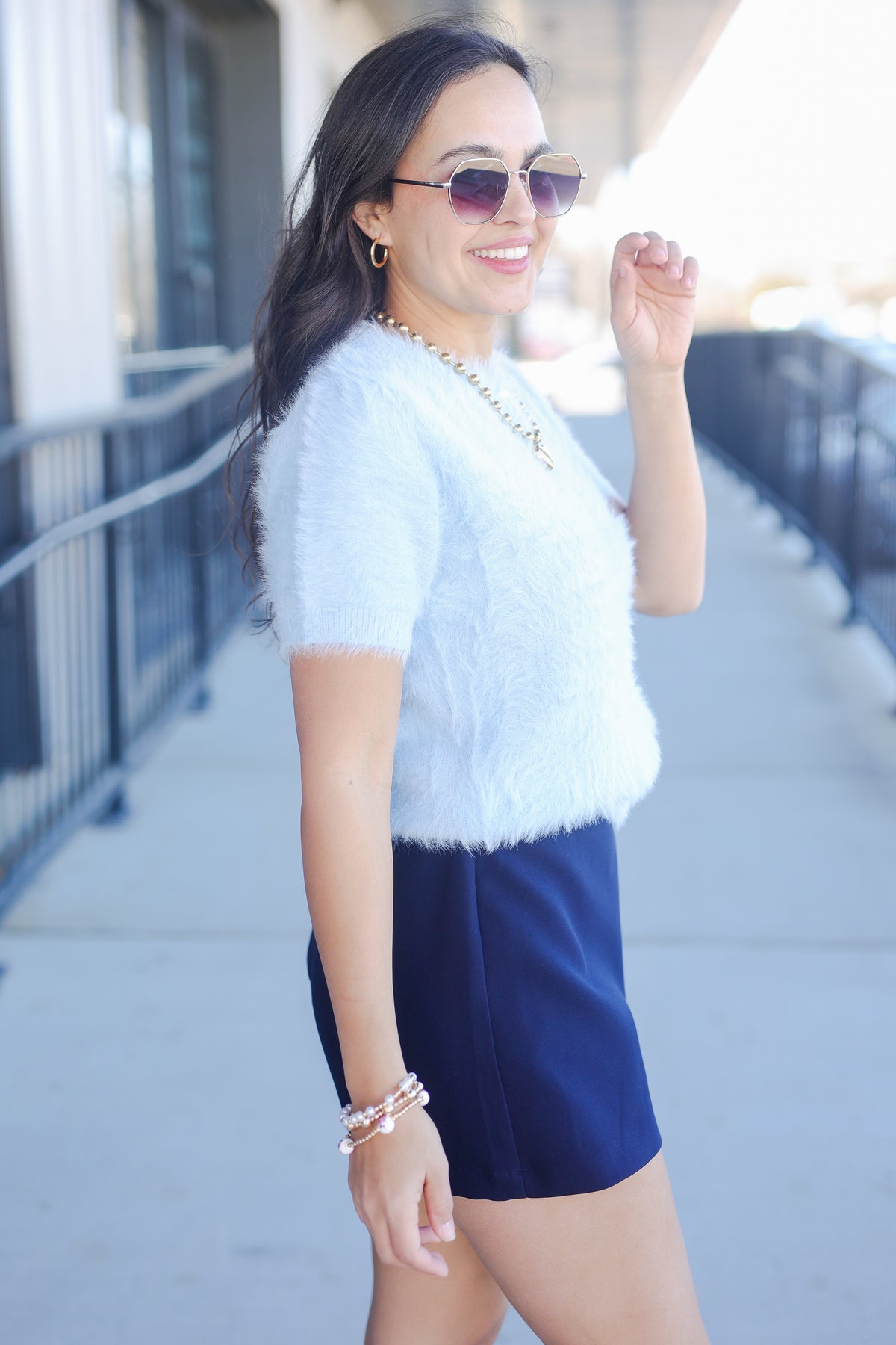 Woman wearing a white top and navy shorts outdoors
