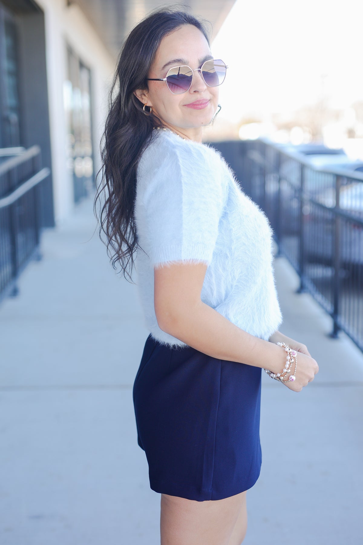 Woman wearing a white sweater and navy skirt outdoors