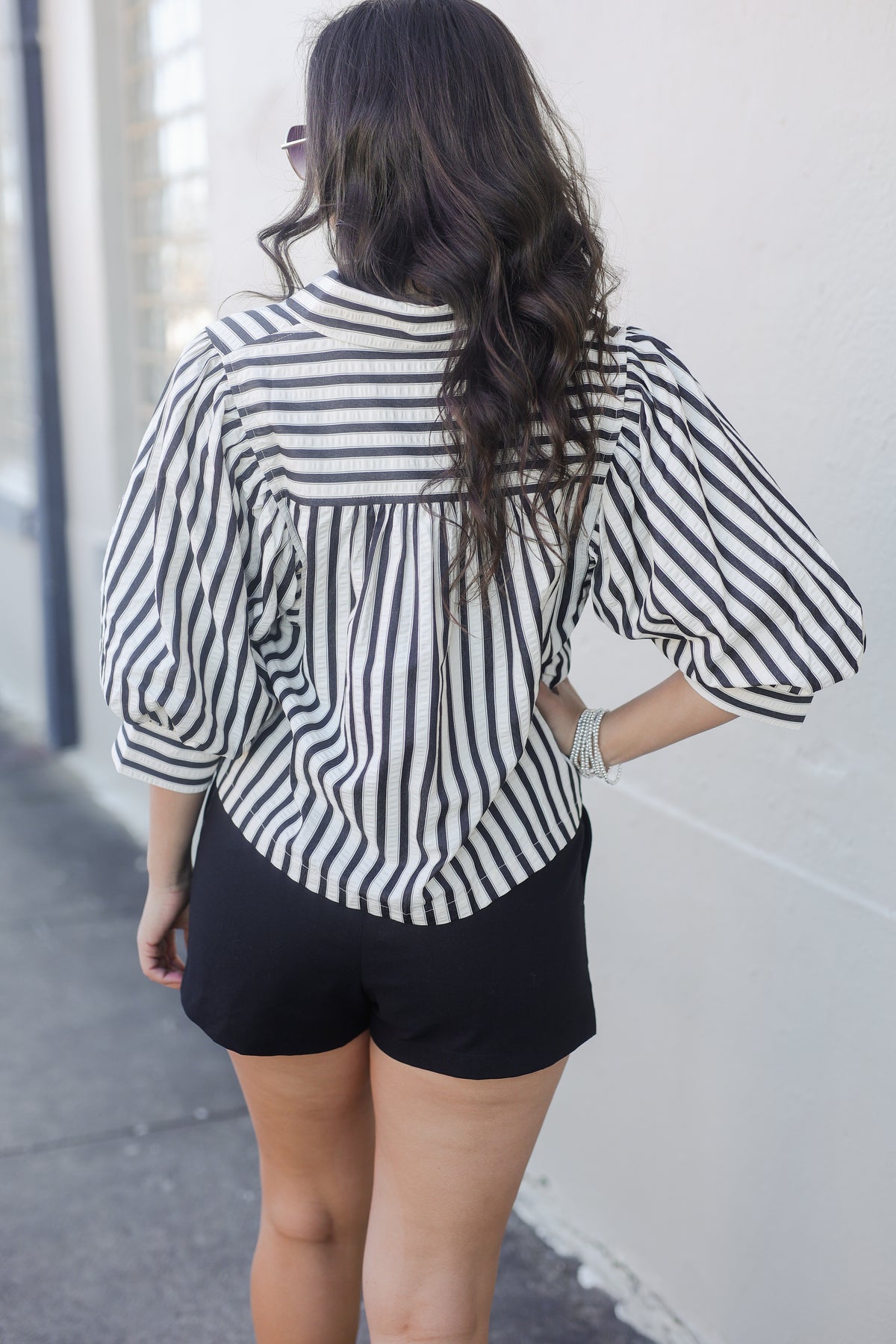 Person wearing a black and white striped shirt and black shorts against a light-colored wall.