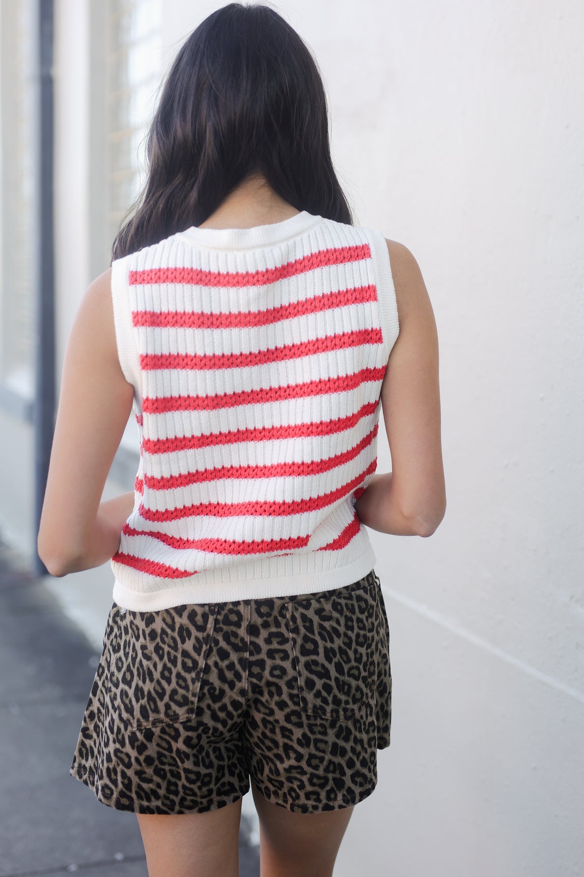 Person wearing a red and white striped sleeveless top with leopard print shorts against a light background