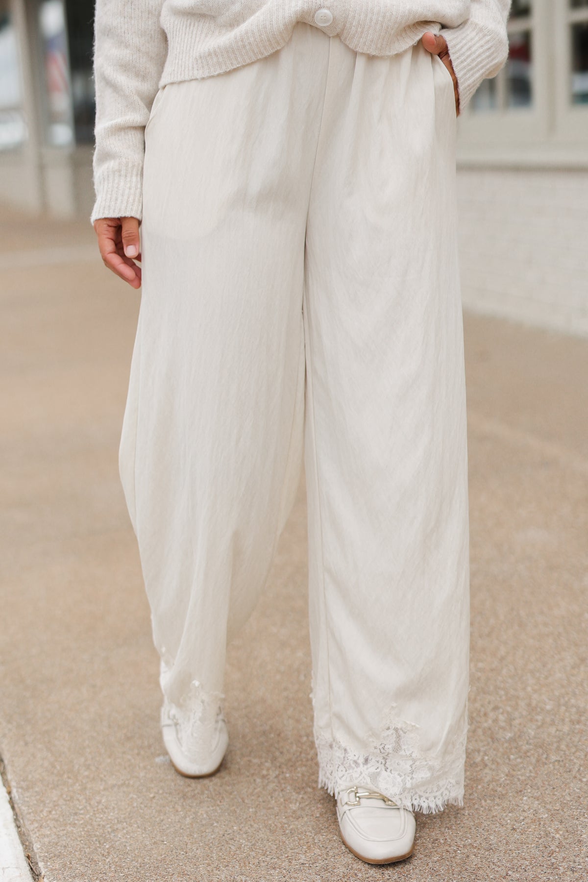 Close up of a model wearing the Ellison Lace Pants – Ecru standing outside. Southern House Clothing