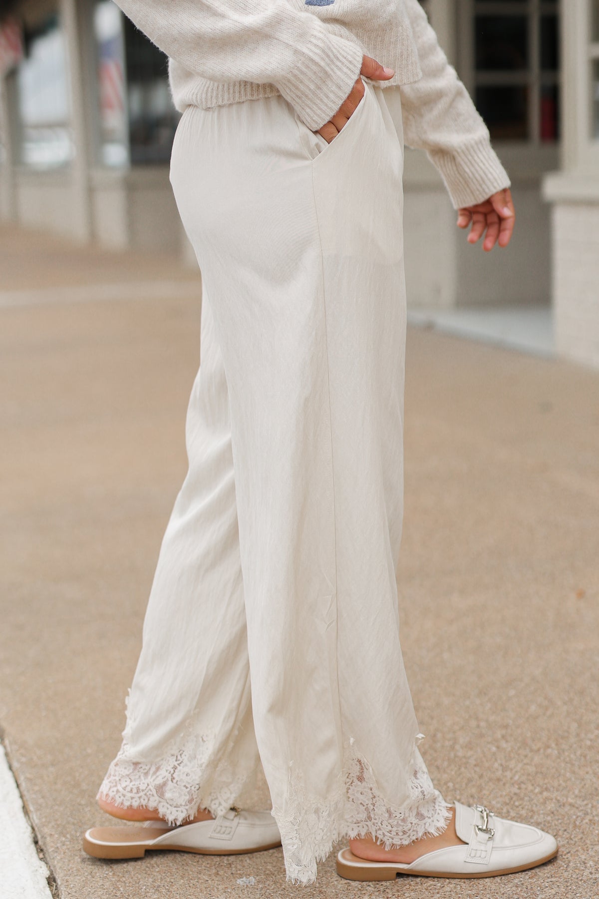 Close up of a model wearing the Ellison Lace Pants – Ecru standing outside. Southern House Clothing
