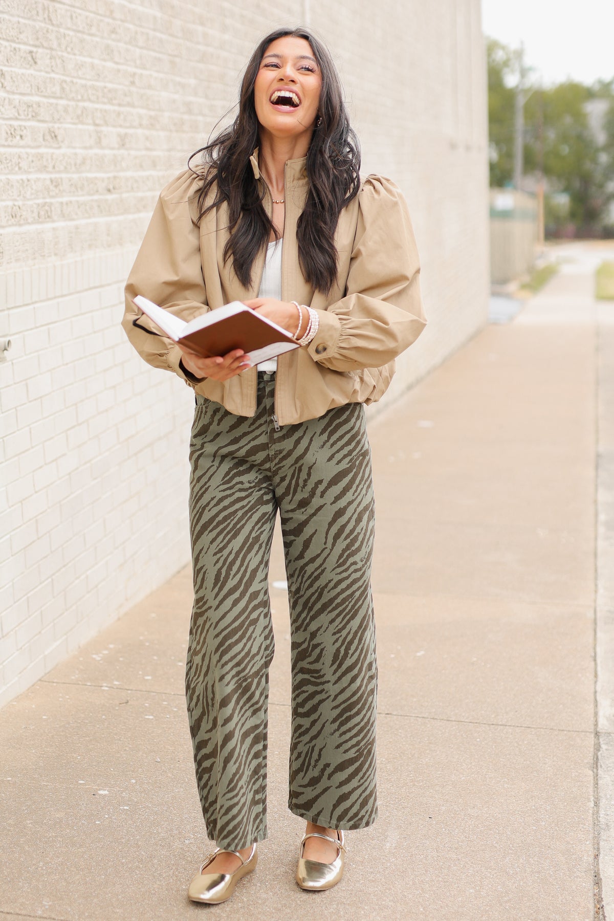 Winscott Puff Sleeve Zip Jacket in Khaki styled with Safari Stroll Wide Leg Pants in olive animal print and metallic gold ballet flats, showing the cropped fit and puff sleeves. Southern House Clothing