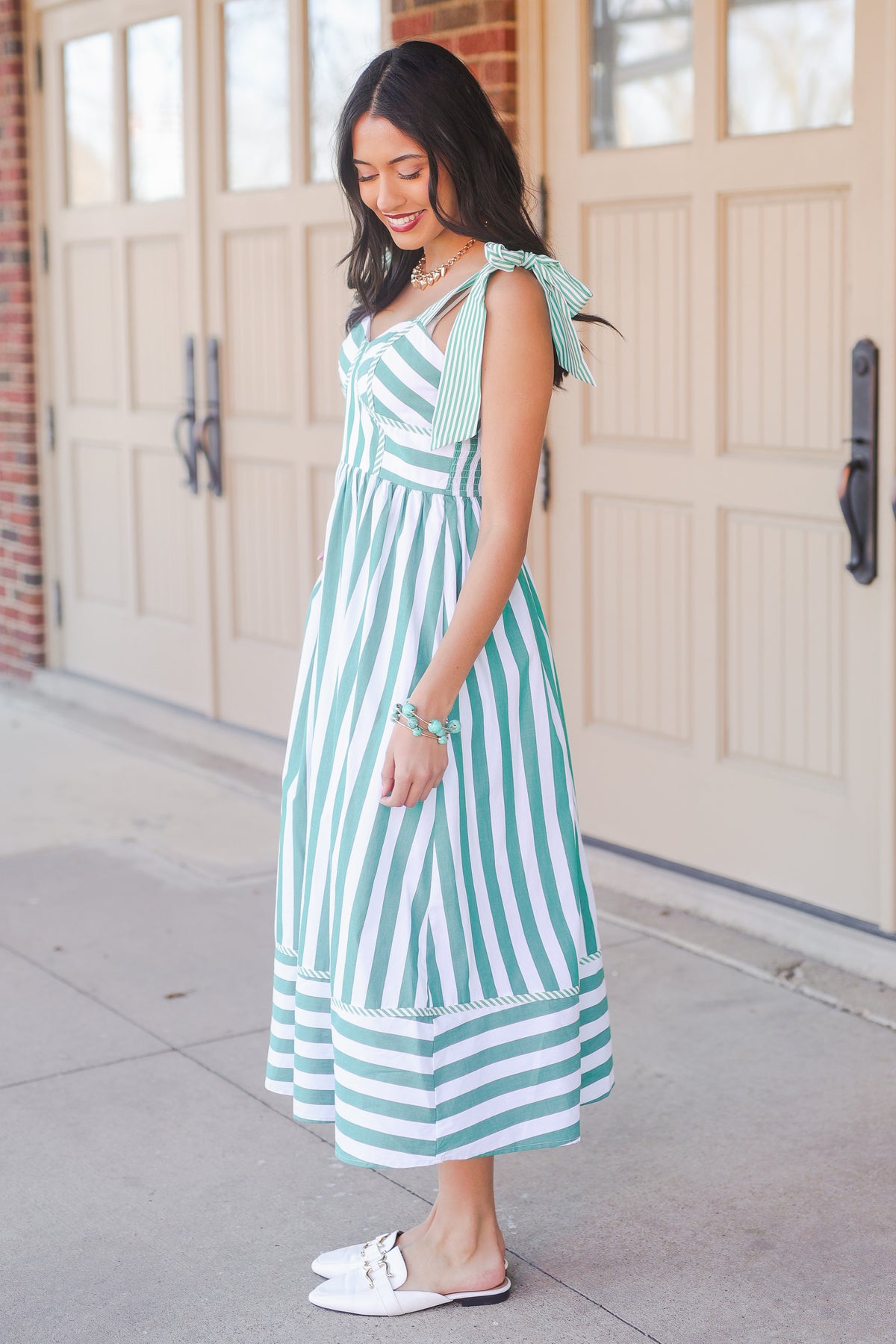 Woman wearing a green and white striped dress standing in front of a garage door.