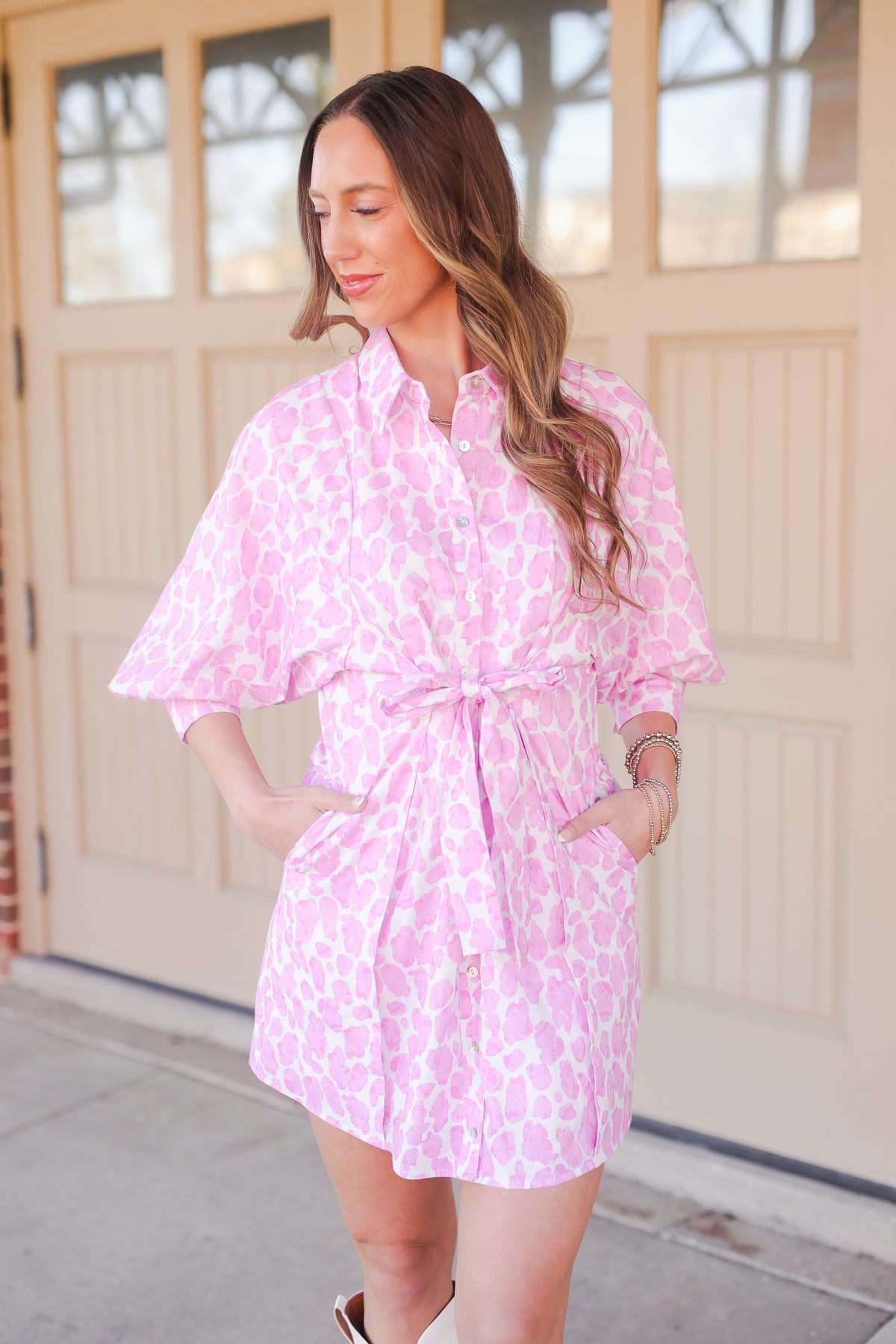 Woman wearing a pink floral dress standing in front of a beige garage door.