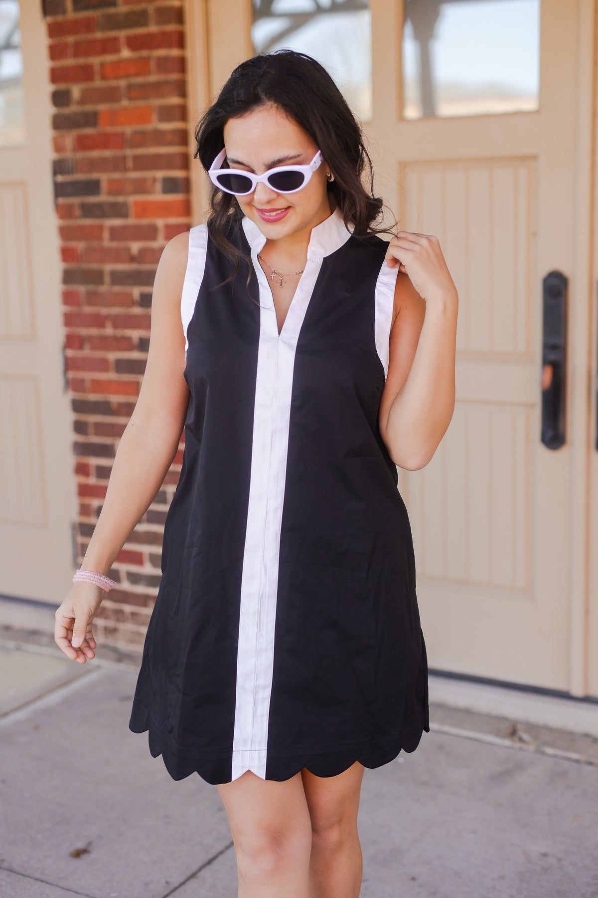 Woman wearing a black and white dress with sunglasses in front of a door.