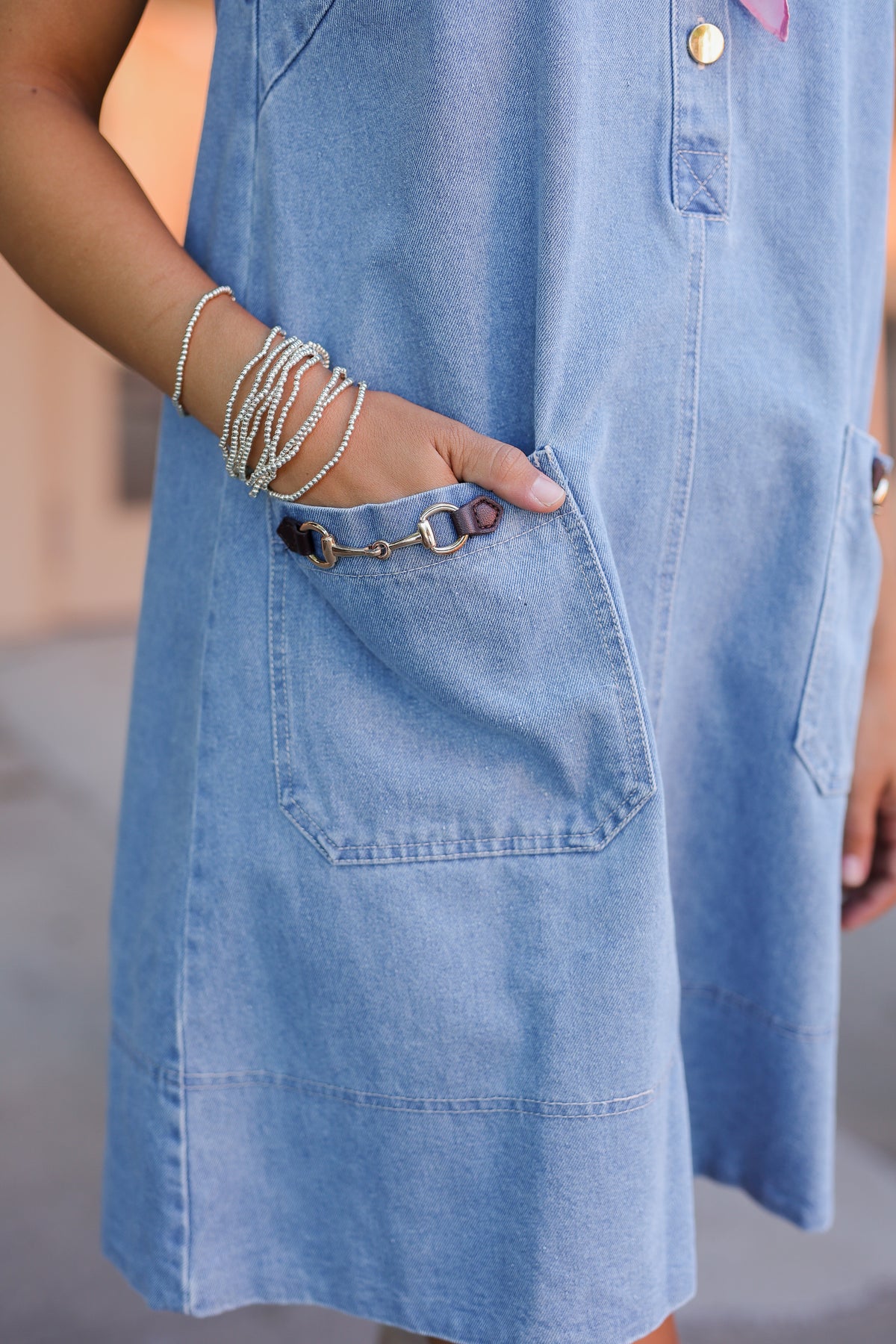 Person wearing a light blue denim dress with a blurred background