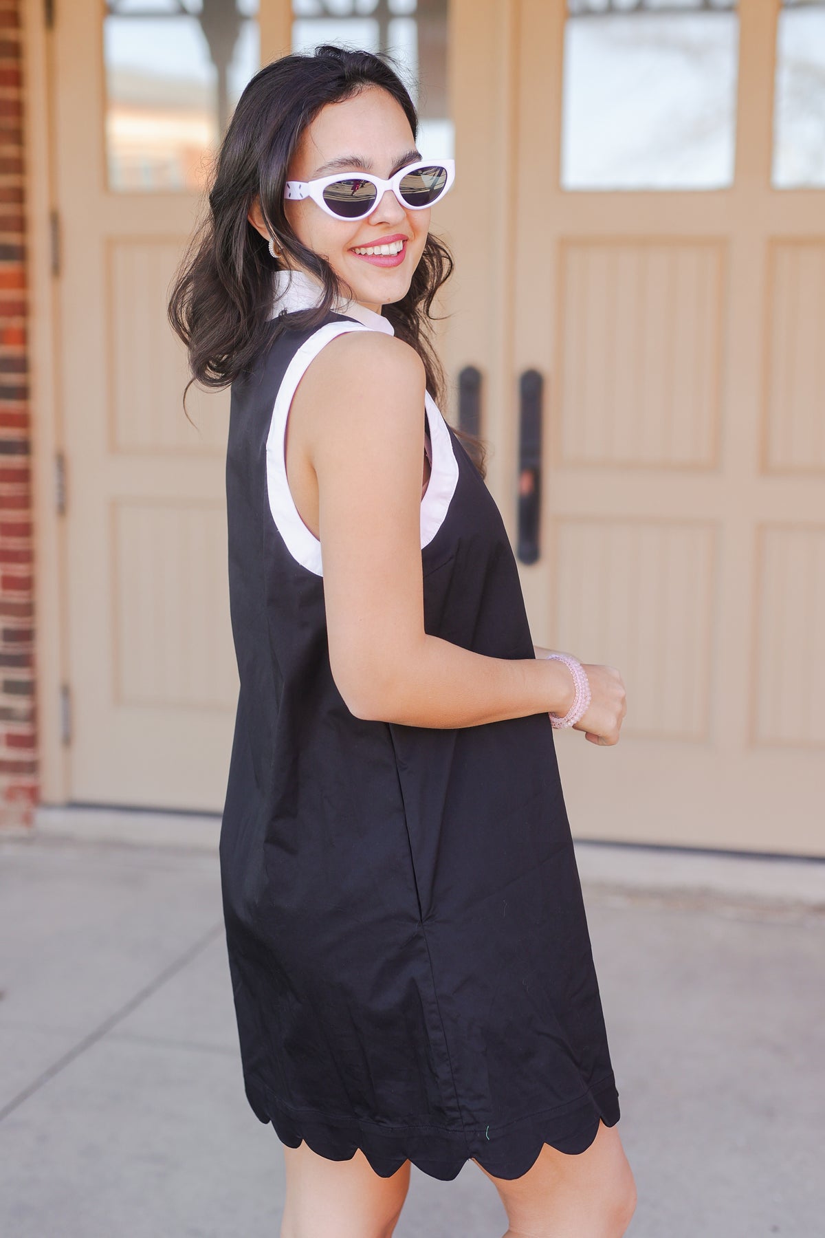 Woman wearing a black dress with white trim in front of a garage door.