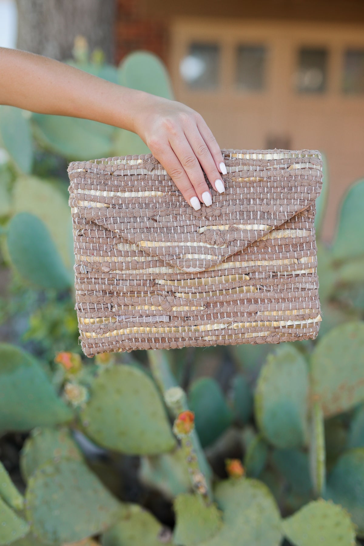 Woman holding a brown and gold clutch.