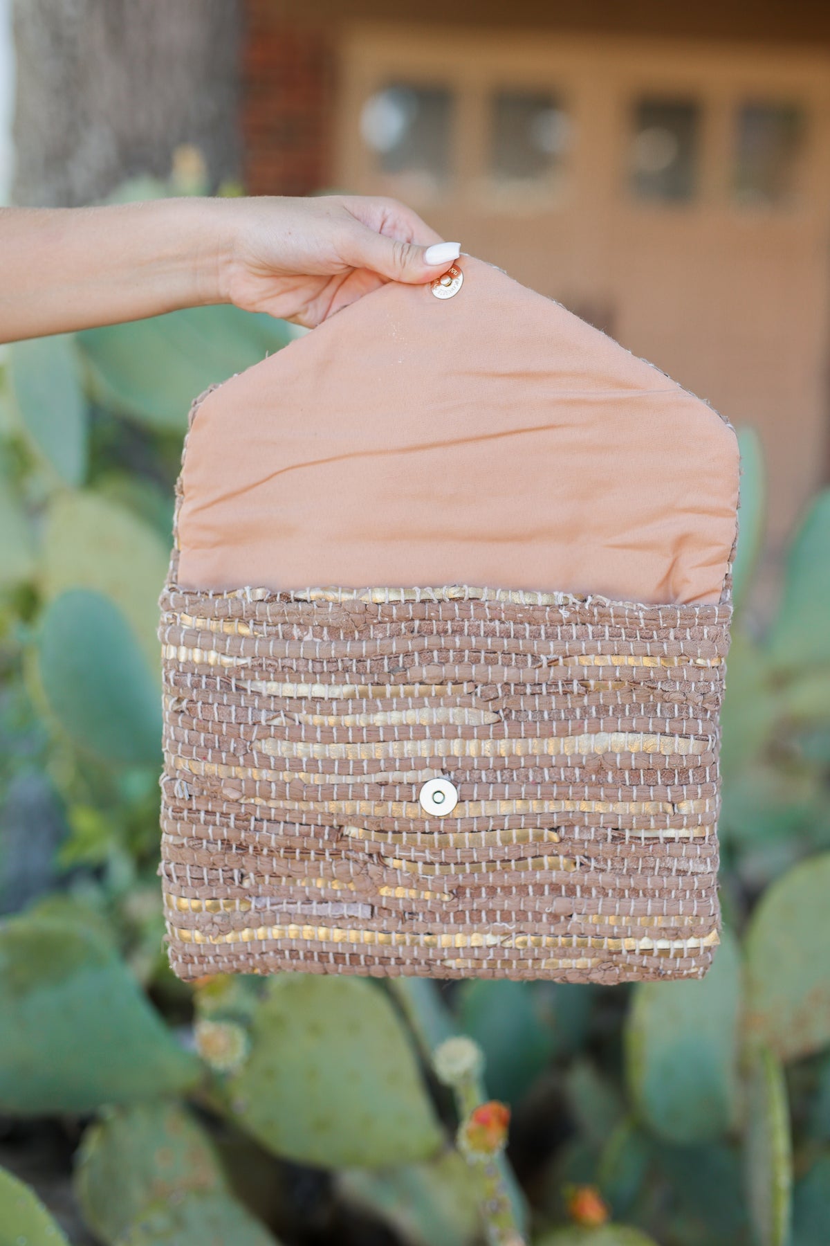 Woman holding a brown and gold clutch.