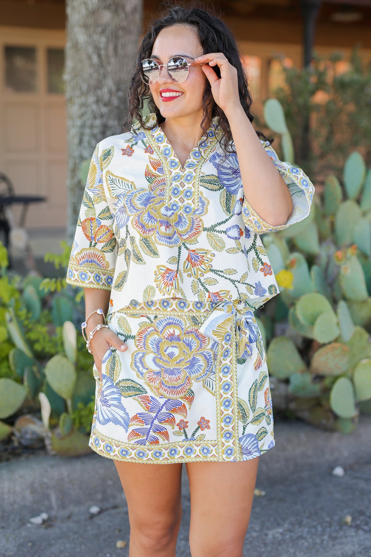 Woman wearing a colorful floral set standing in front of cacti.