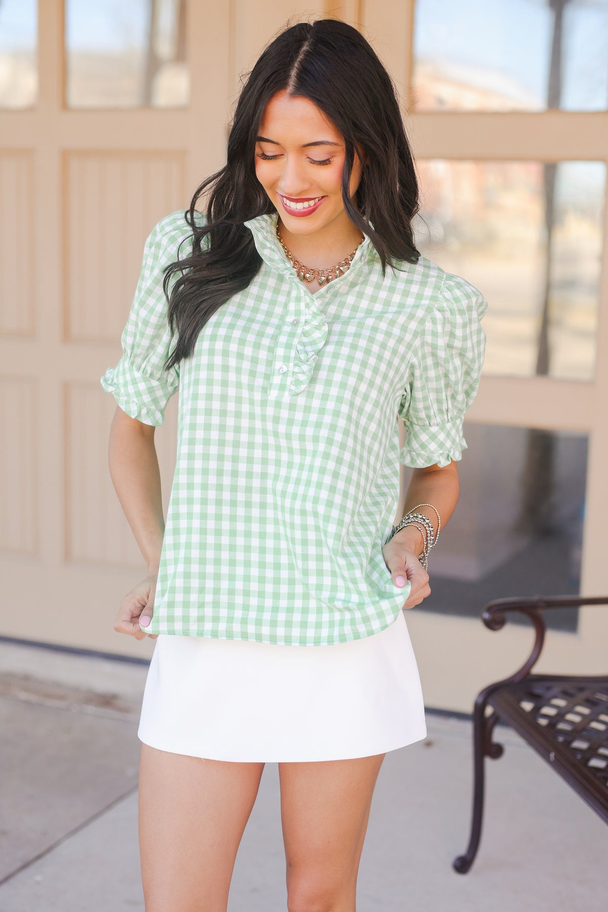 Woman wearing a green checkered blouse and white skirt outdoors.