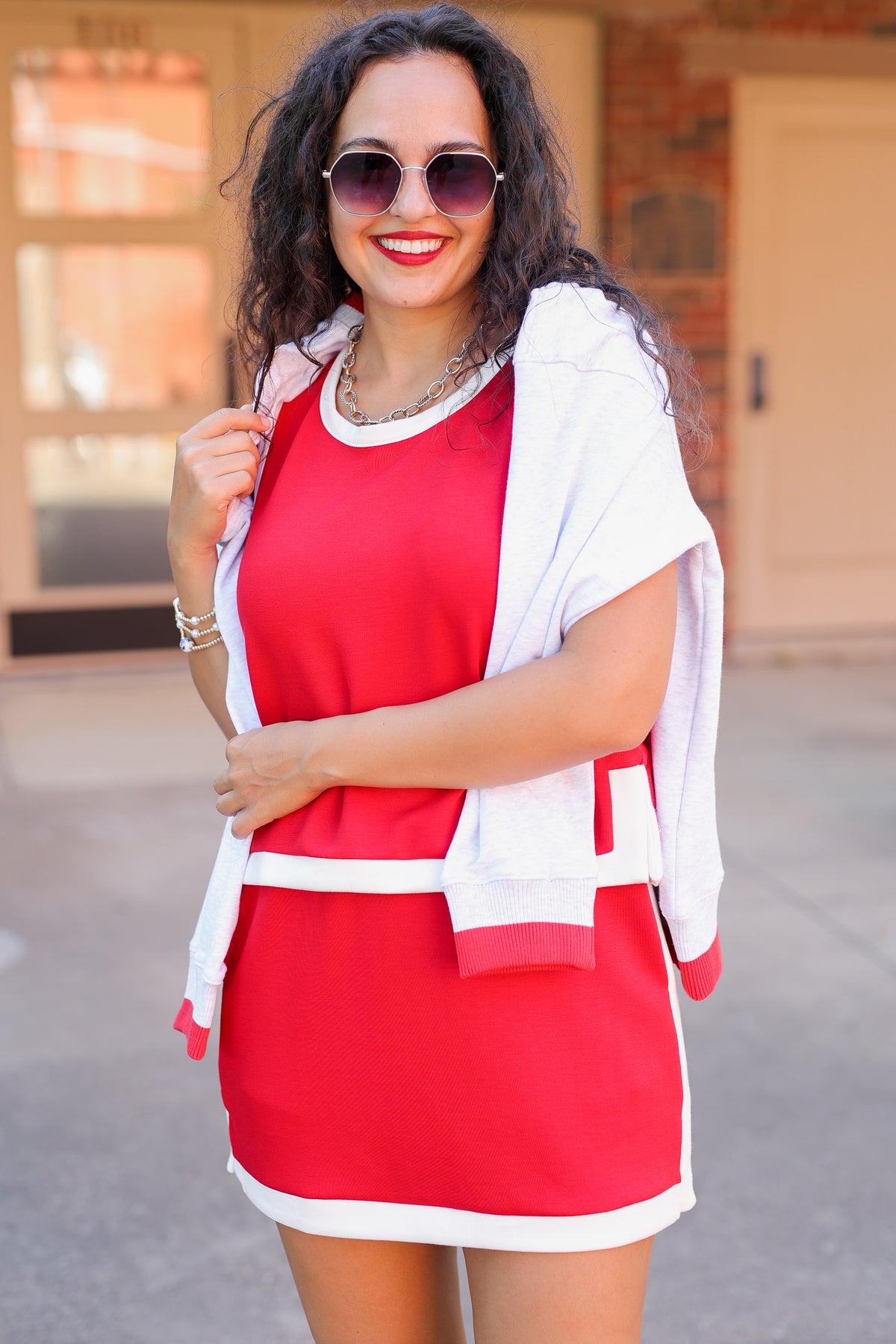 Woman wearing a red dress with a white cardigan outdoors