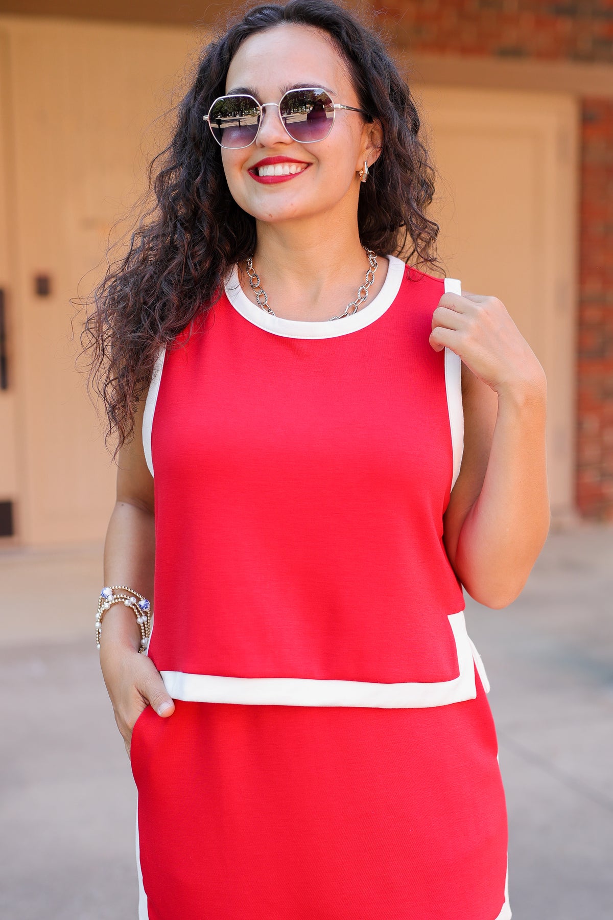Woman wearing a red set with white trim standing outdoors.
