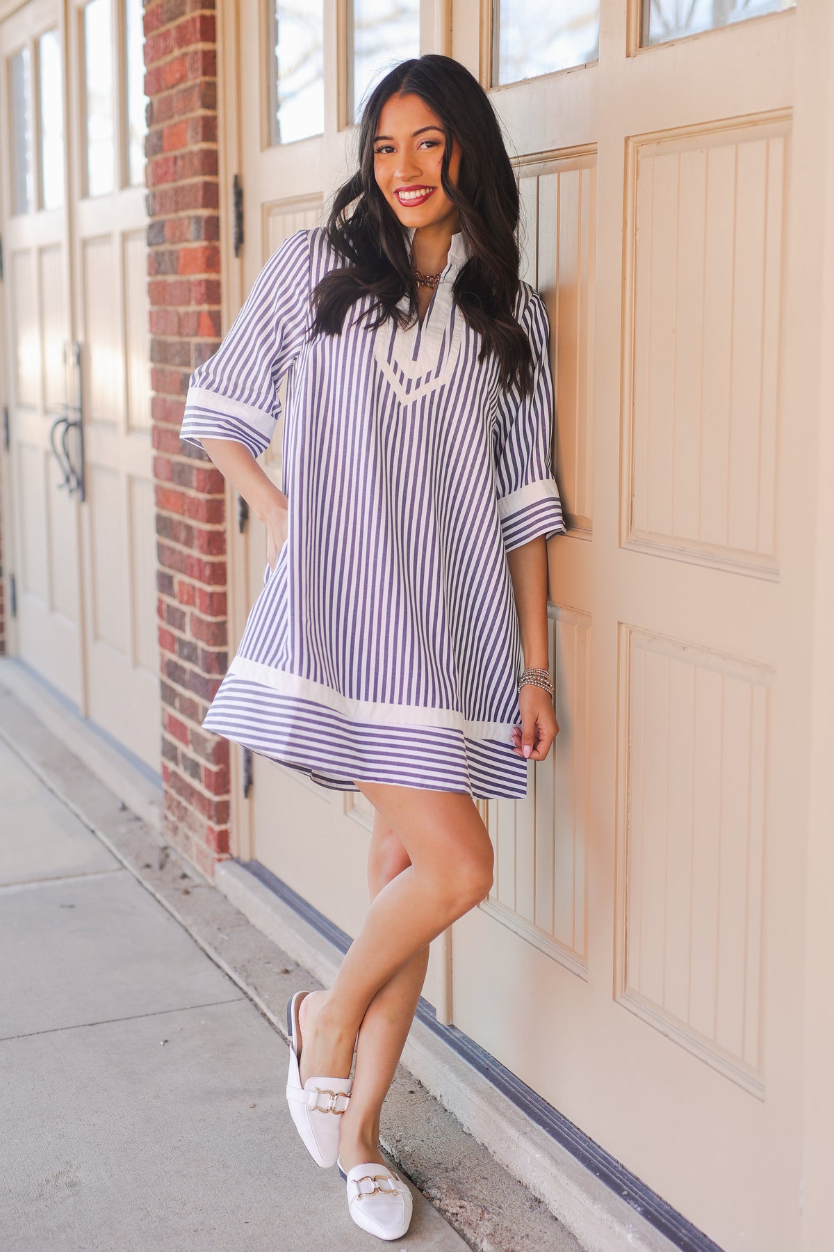 Woman in a striped dress standing in front of a door