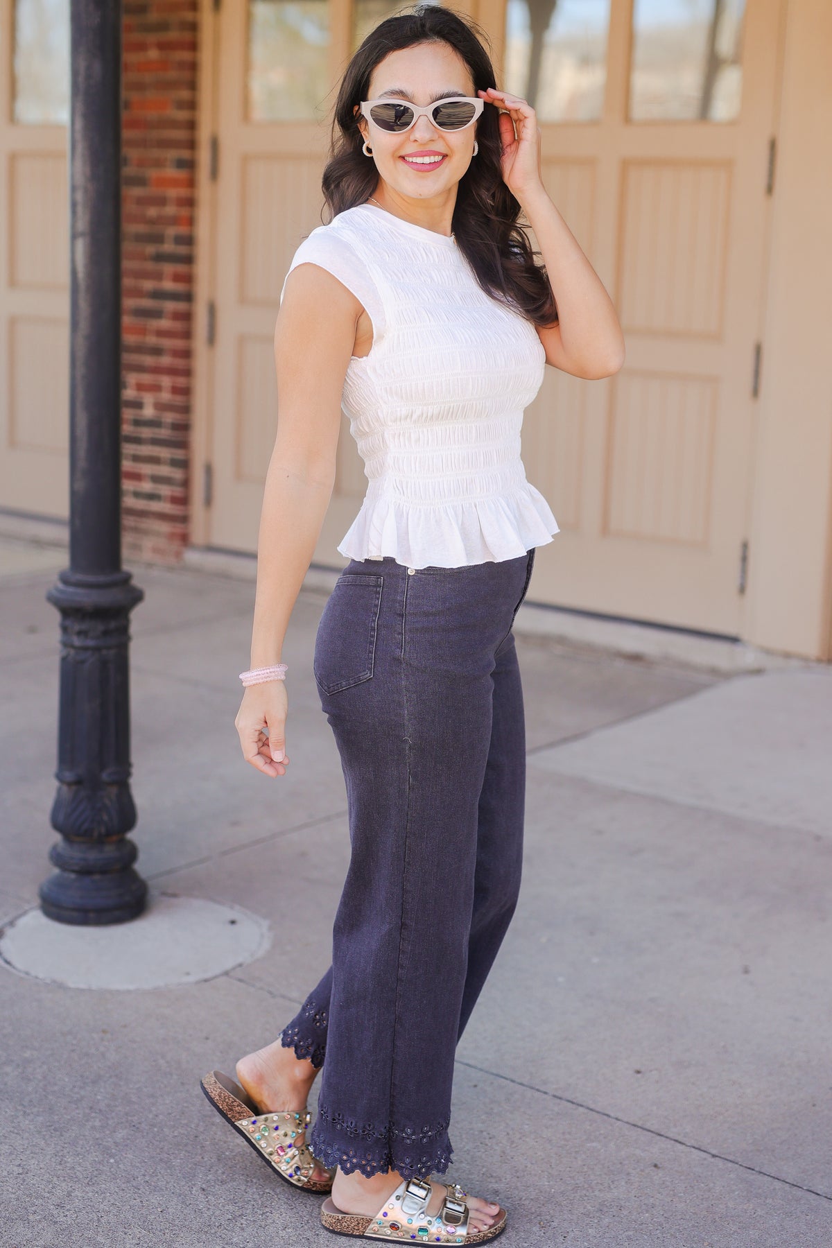 Woman wearing a white top and dark pants on a sidewalk.