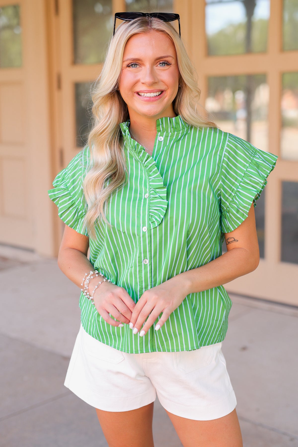 Woman wearing a green and white striped blouse with ruffled sleeves outdoors.