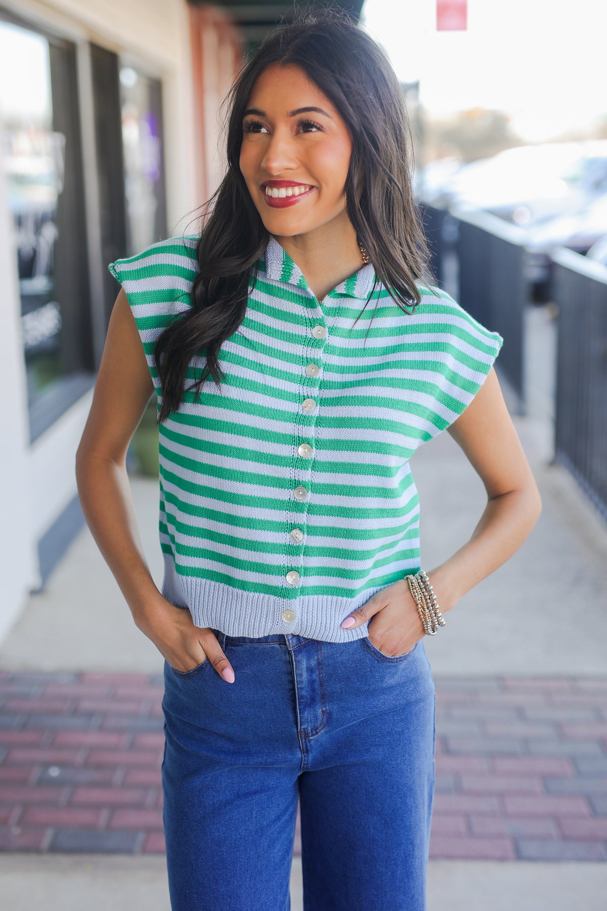 Woman wearing a green and white striped shirt with blue jeans outdoors.