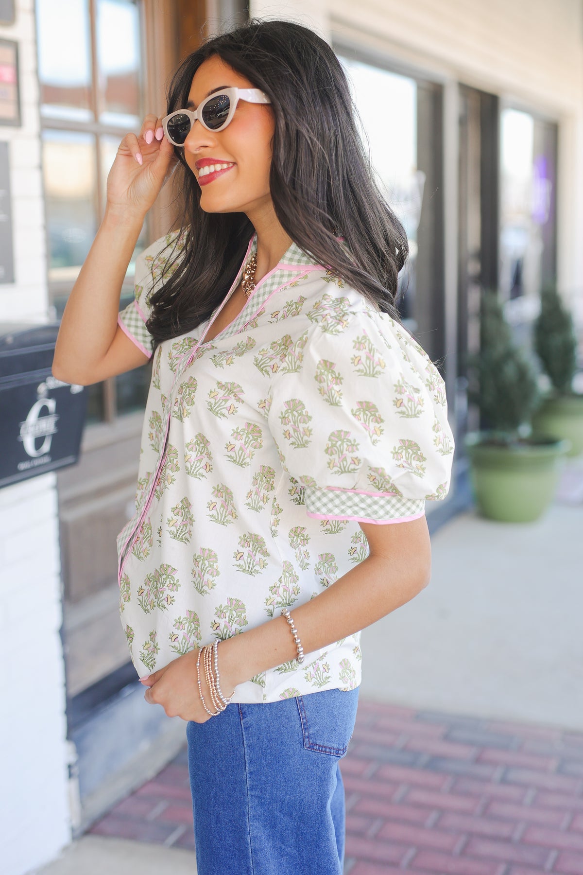 Woman wearing a floral blouse and sunglasses outdoors