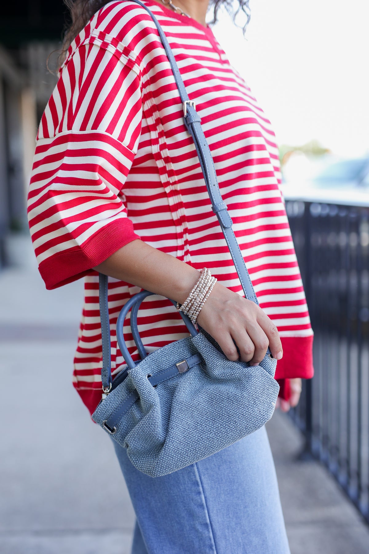 Person wearing a red and white striped shirt holding a blue handbag.