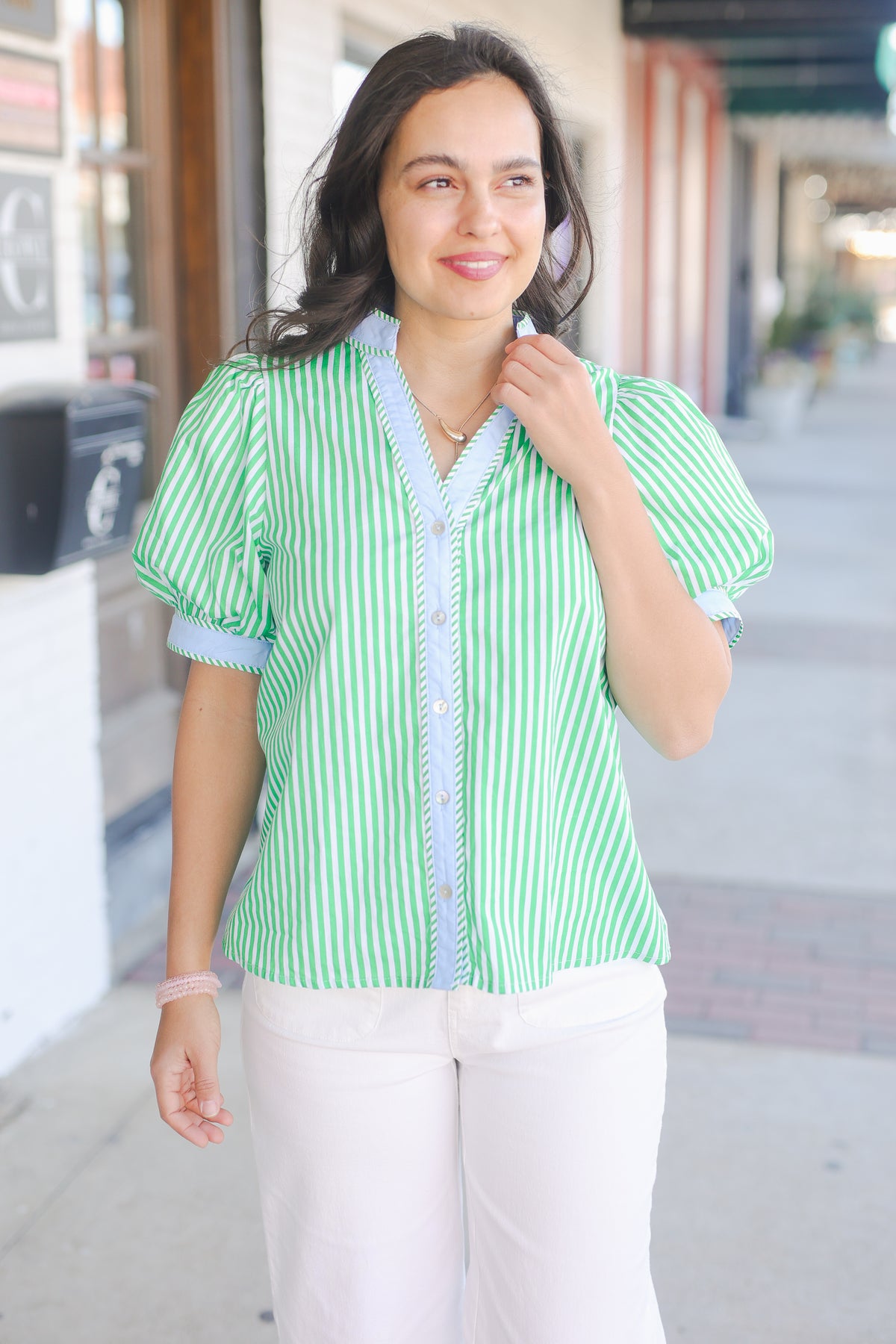 Woman wearing a green and white striped shirt on a city street.