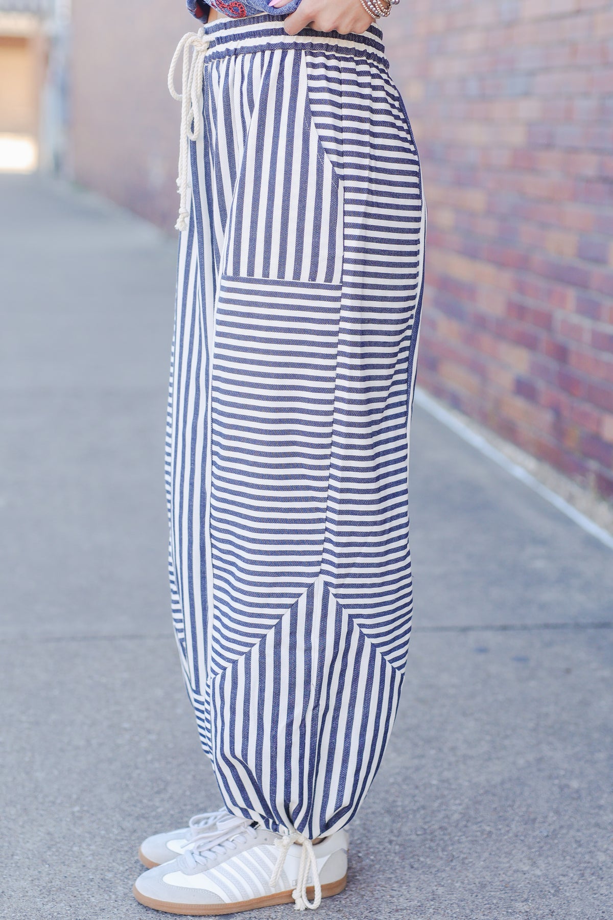 Blue and white striped pants worn by a person on a sidewalk.