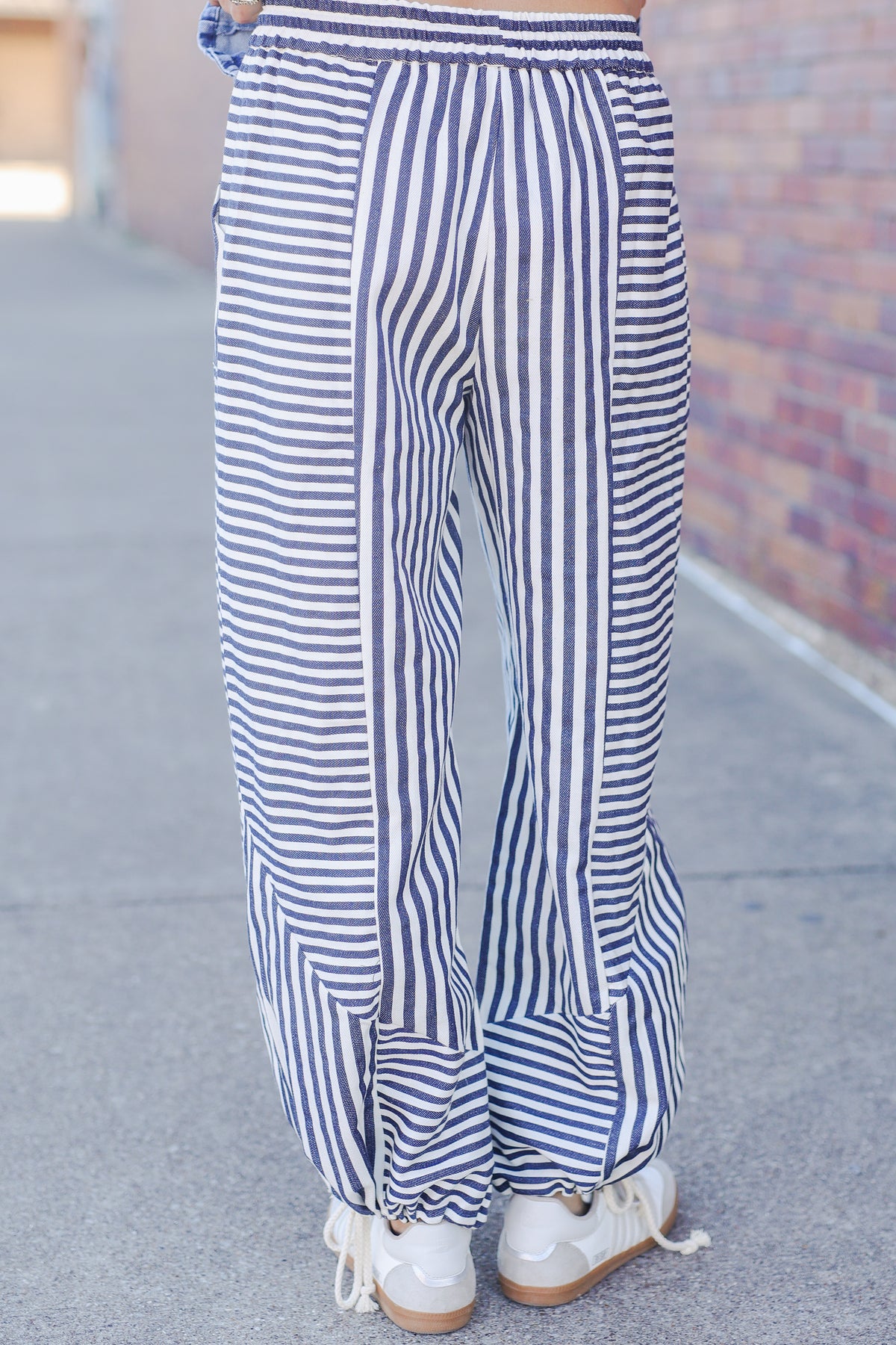 Blue and white striped pants worn by a person on a sidewalk.