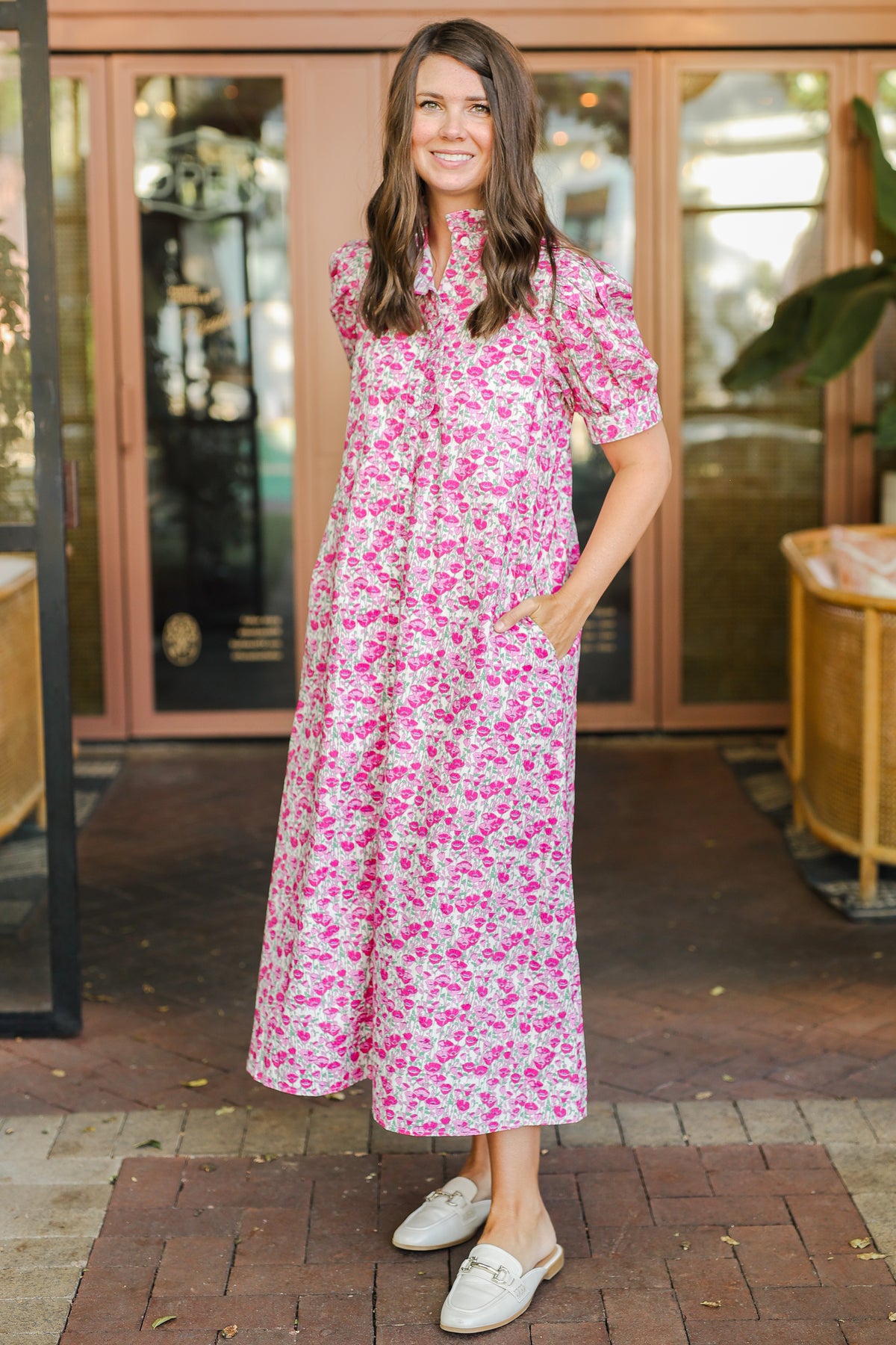 Woman wearing a pink floral dress standing outdoors.