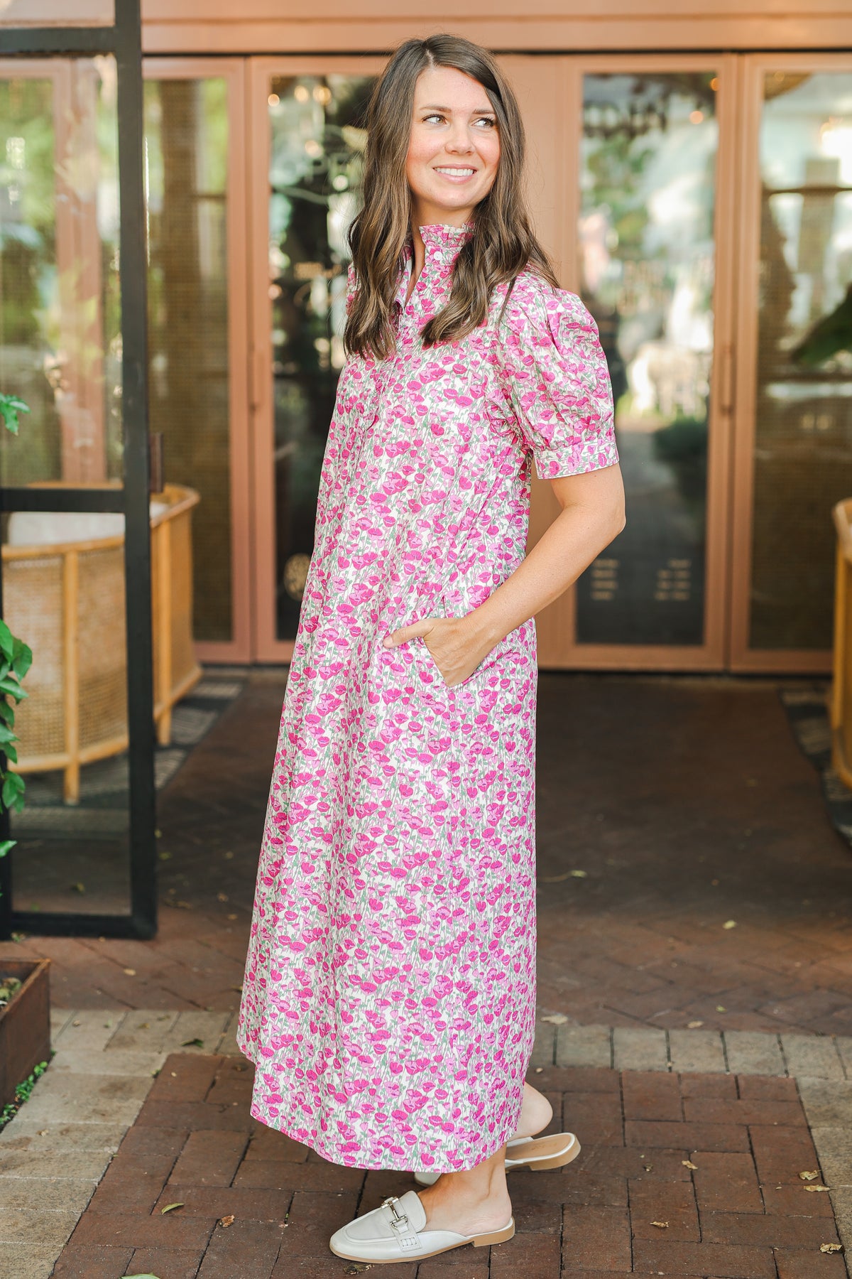 Woman wearing a pink floral dress standing outdoors.