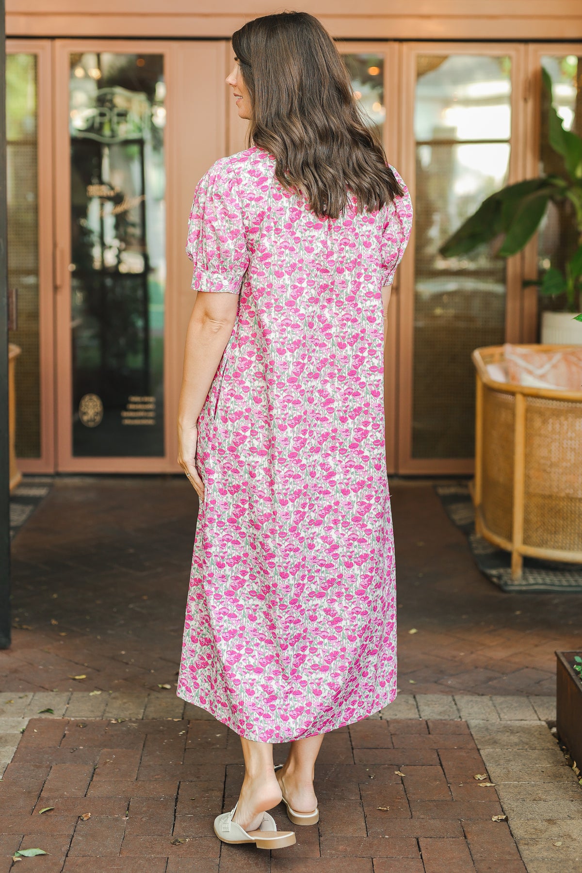 Woman wearing a pink floral dress standing outdoors.
