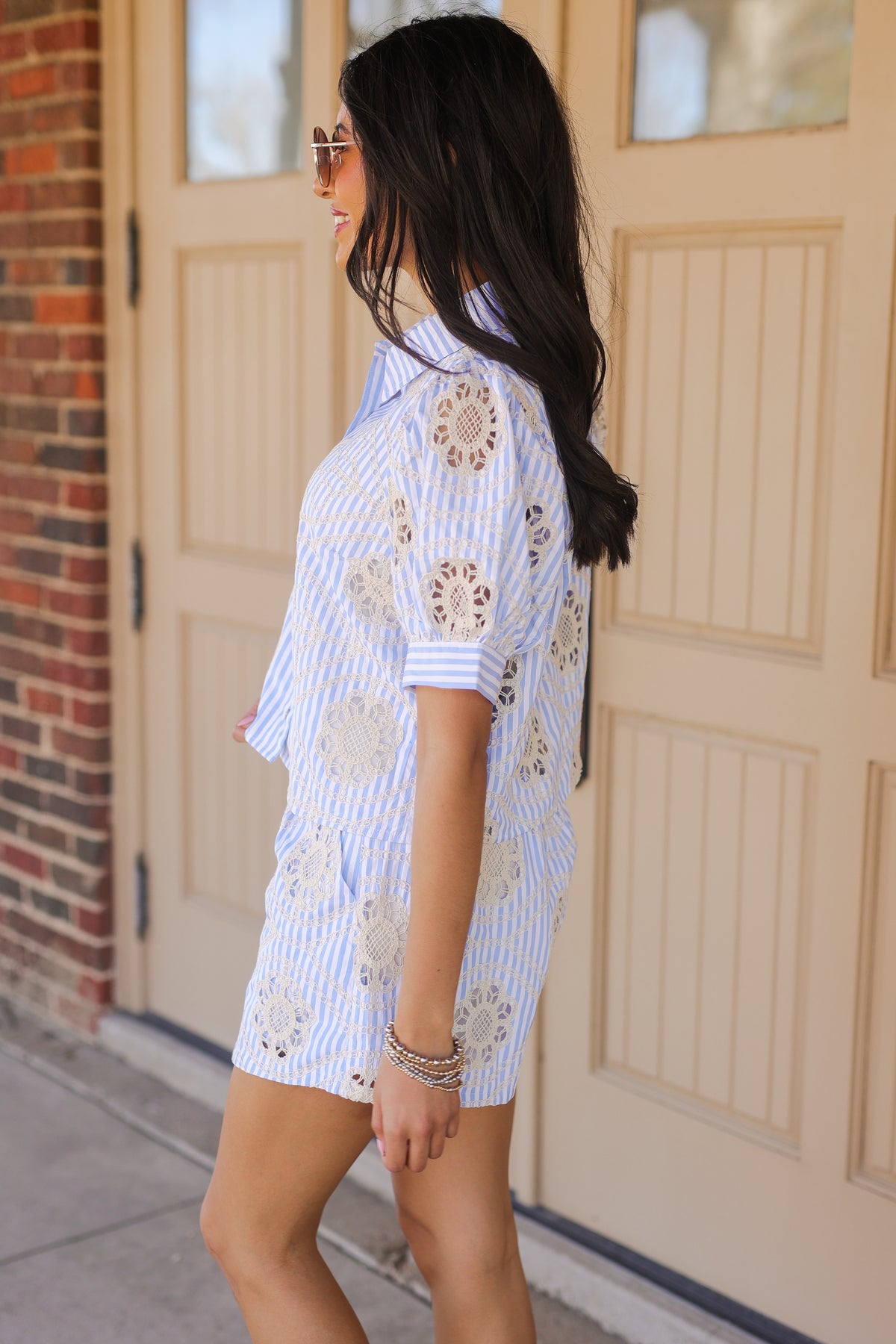 Woman wearing a blue and white floral dress standing in front of a beige door.