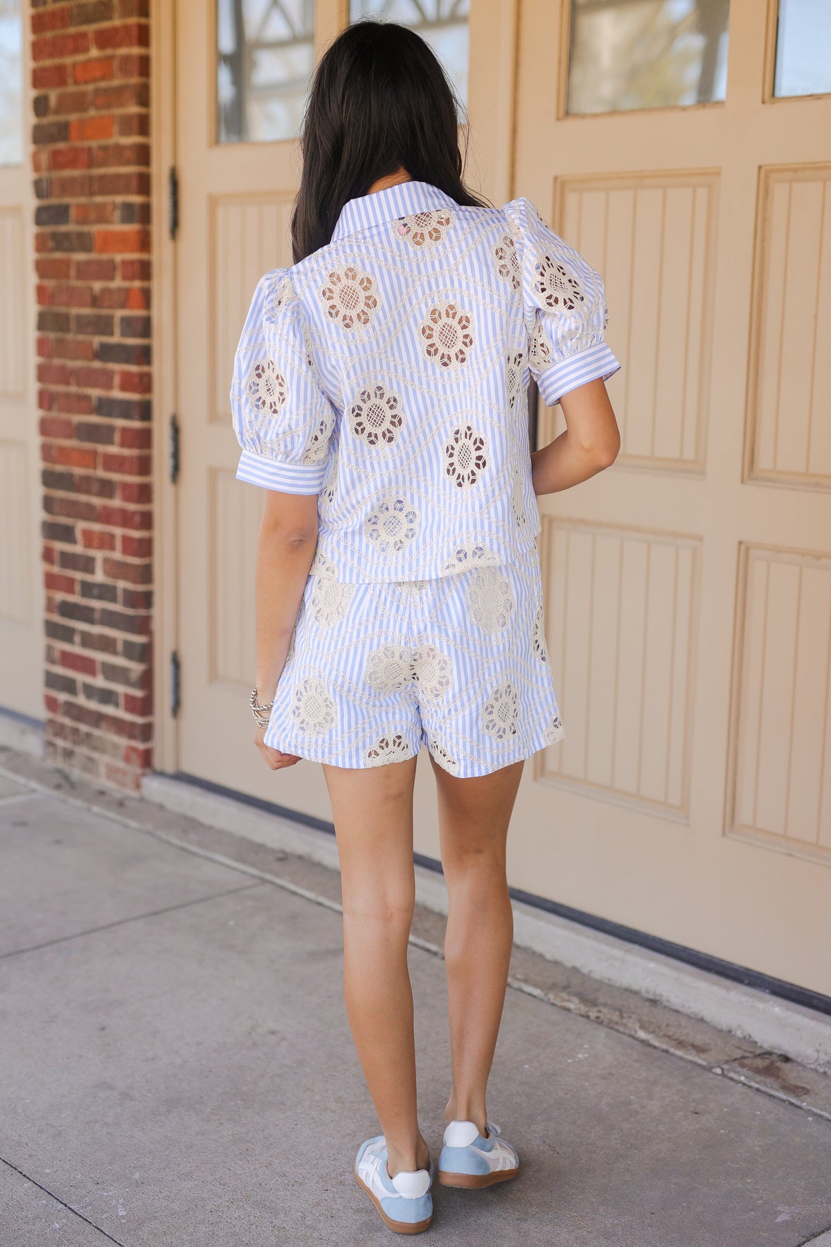 Woman wearing a floral embroidered outfit standing in front of a door.