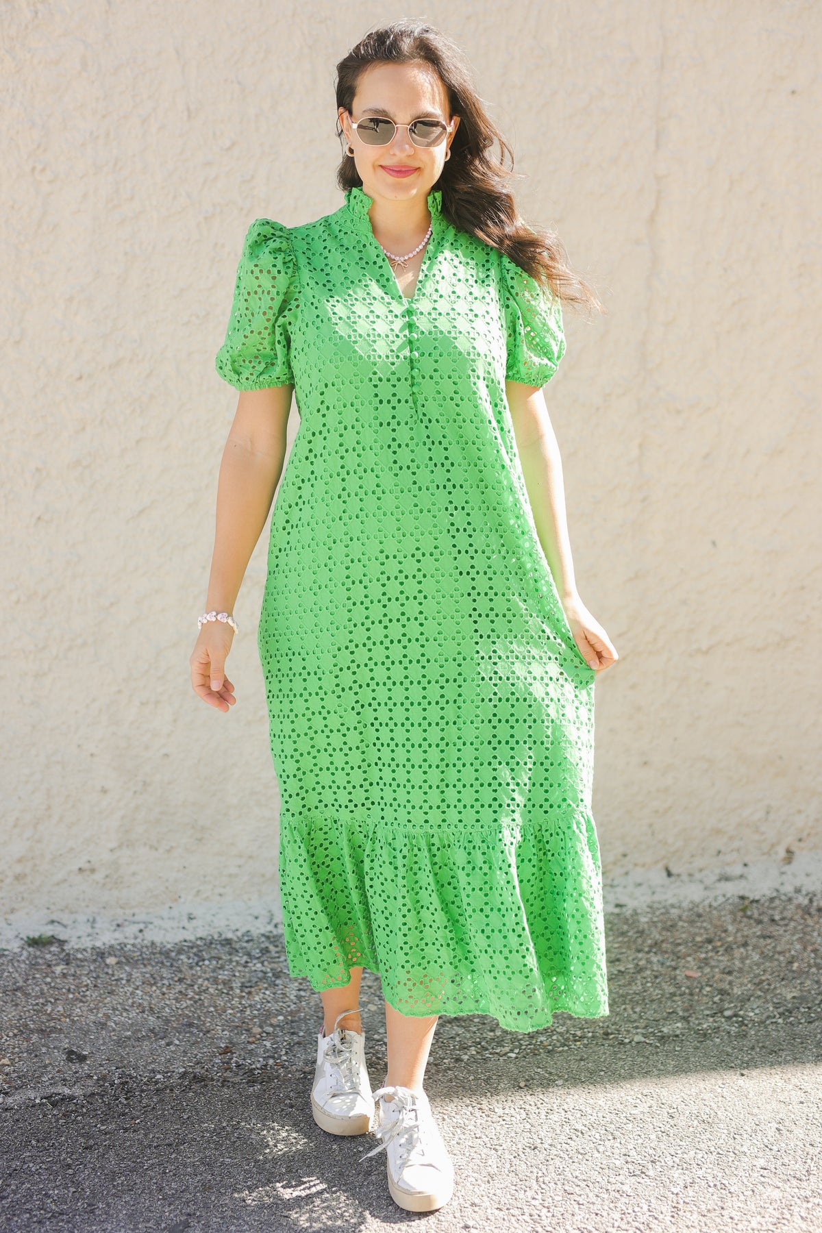 Woman wearing a green dress with a textured pattern against a plain background