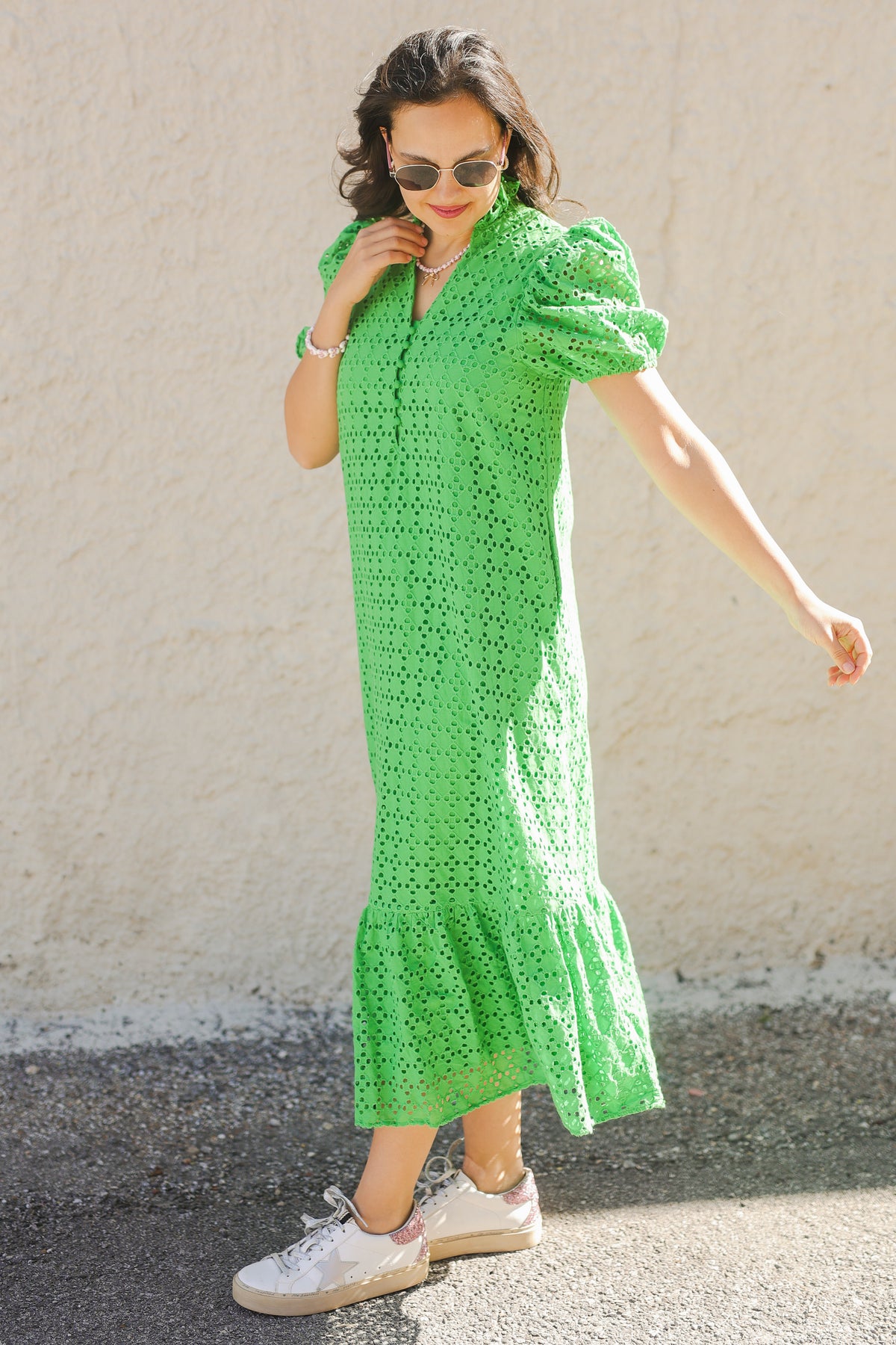 Woman wearing a green dress with puff sleeves against a plain background