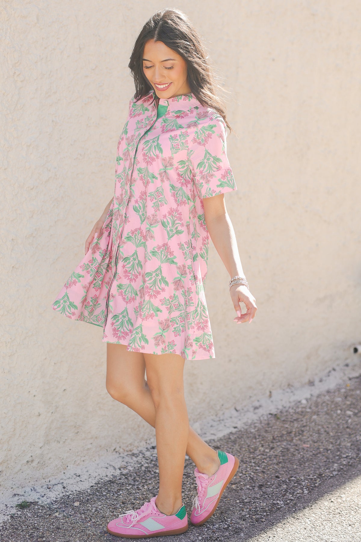 Woman wearing a pink floral dress against a plain background